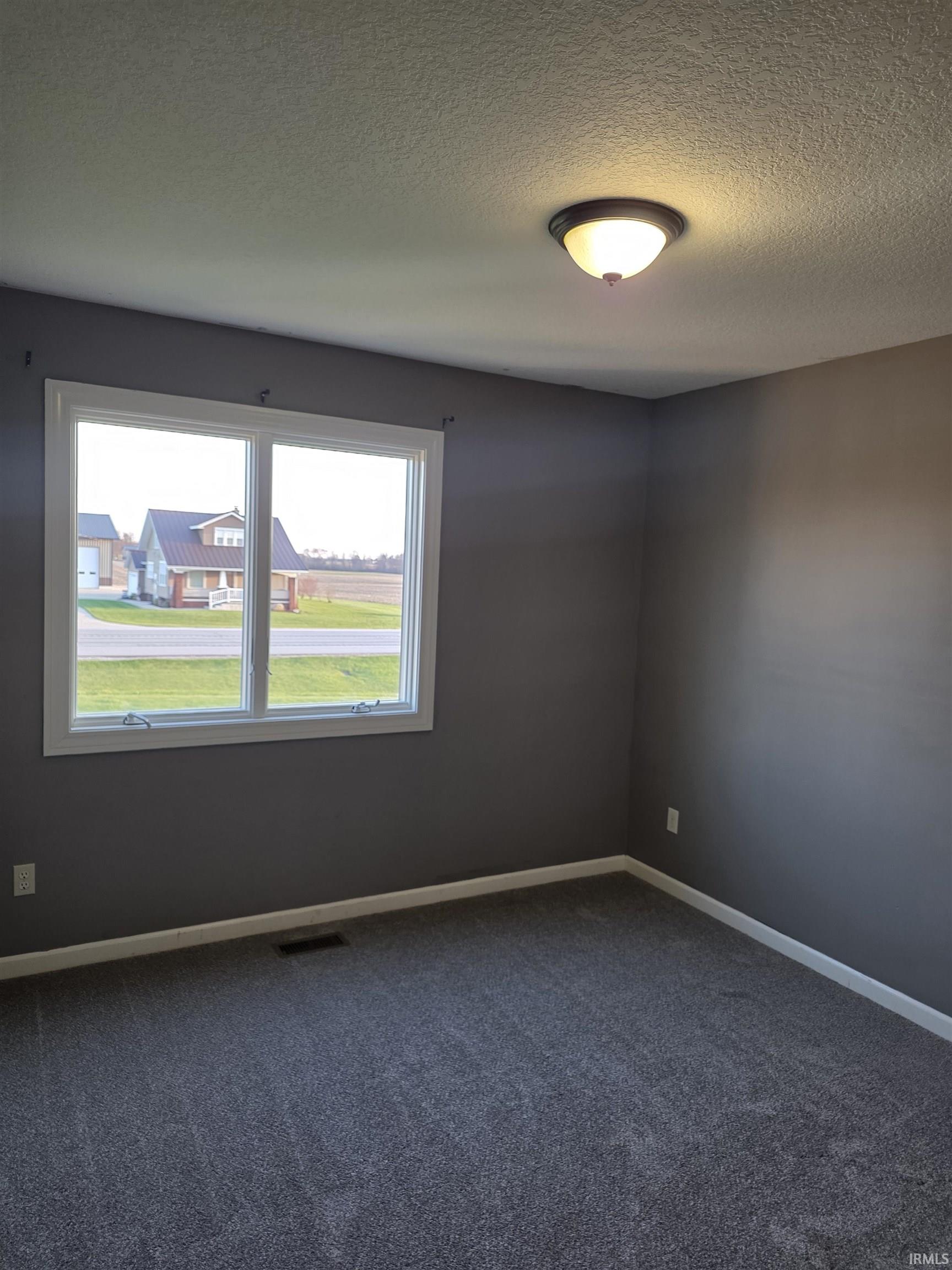 Spare room featuring a textured ceiling and dark colored carpet