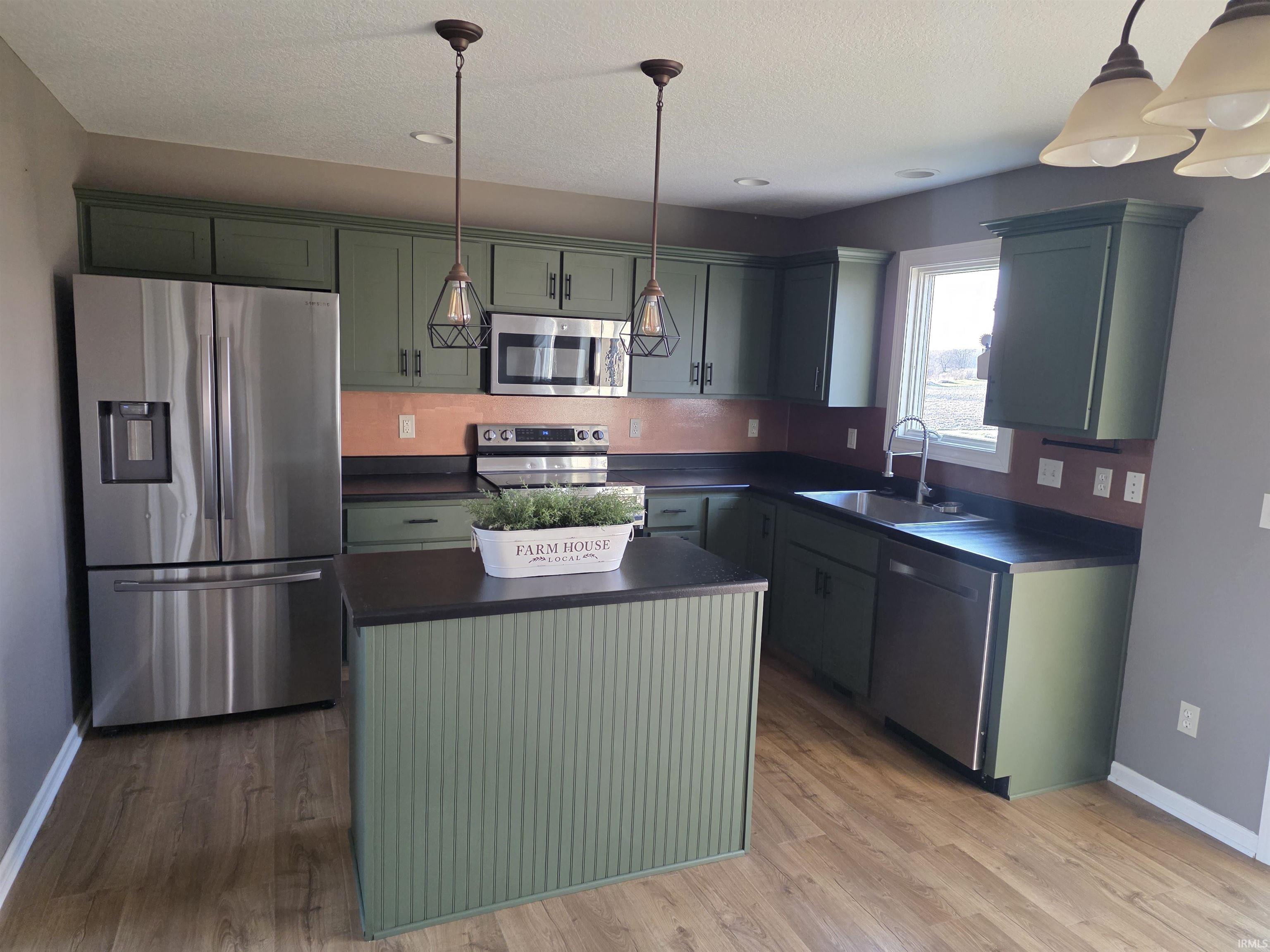 Kitchen featuring green cabinetry, a center island, dark countertops, and stainless steel appliances