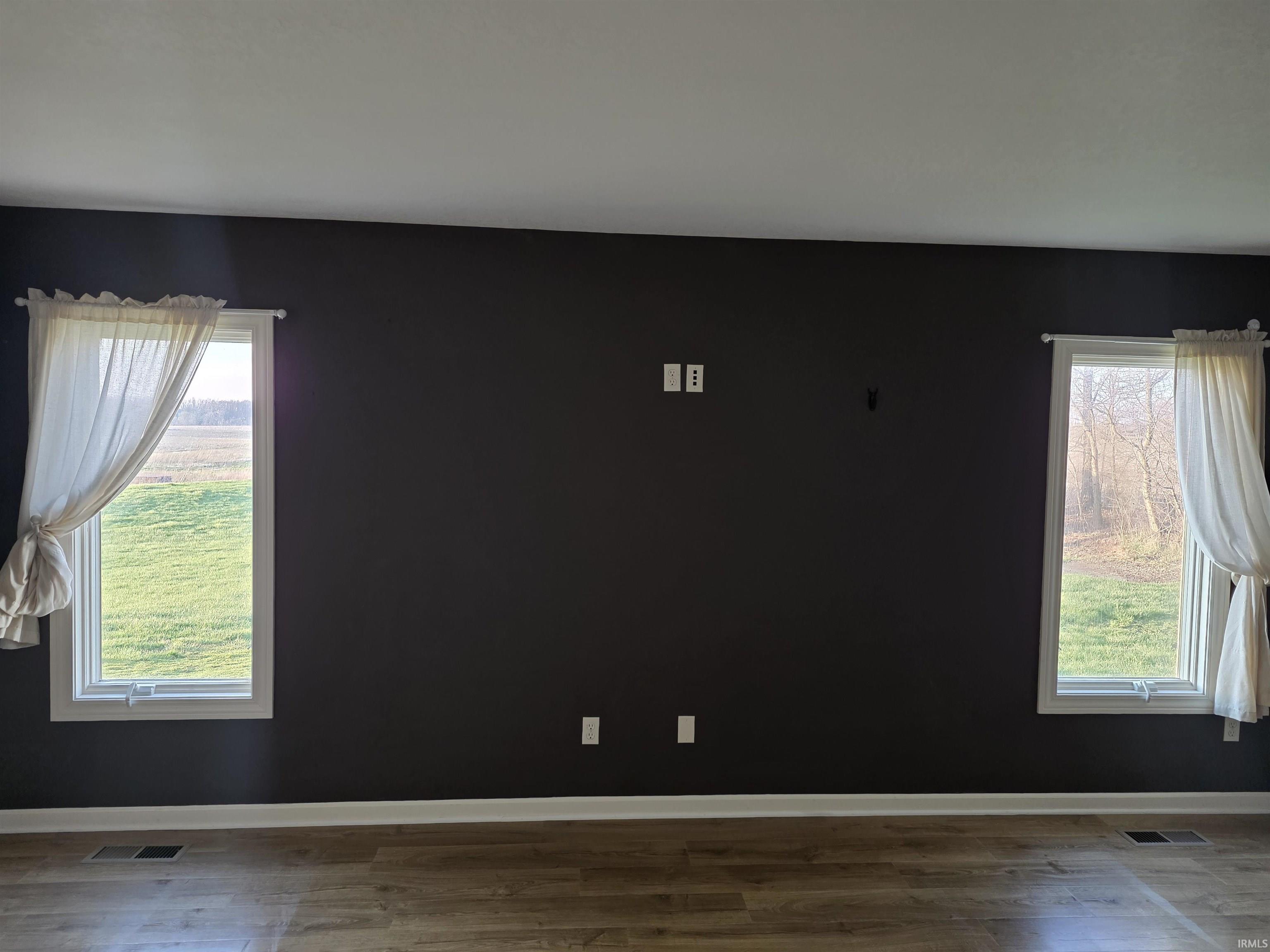 Unfurnished room with wood finished floors and healthy amount of natural light