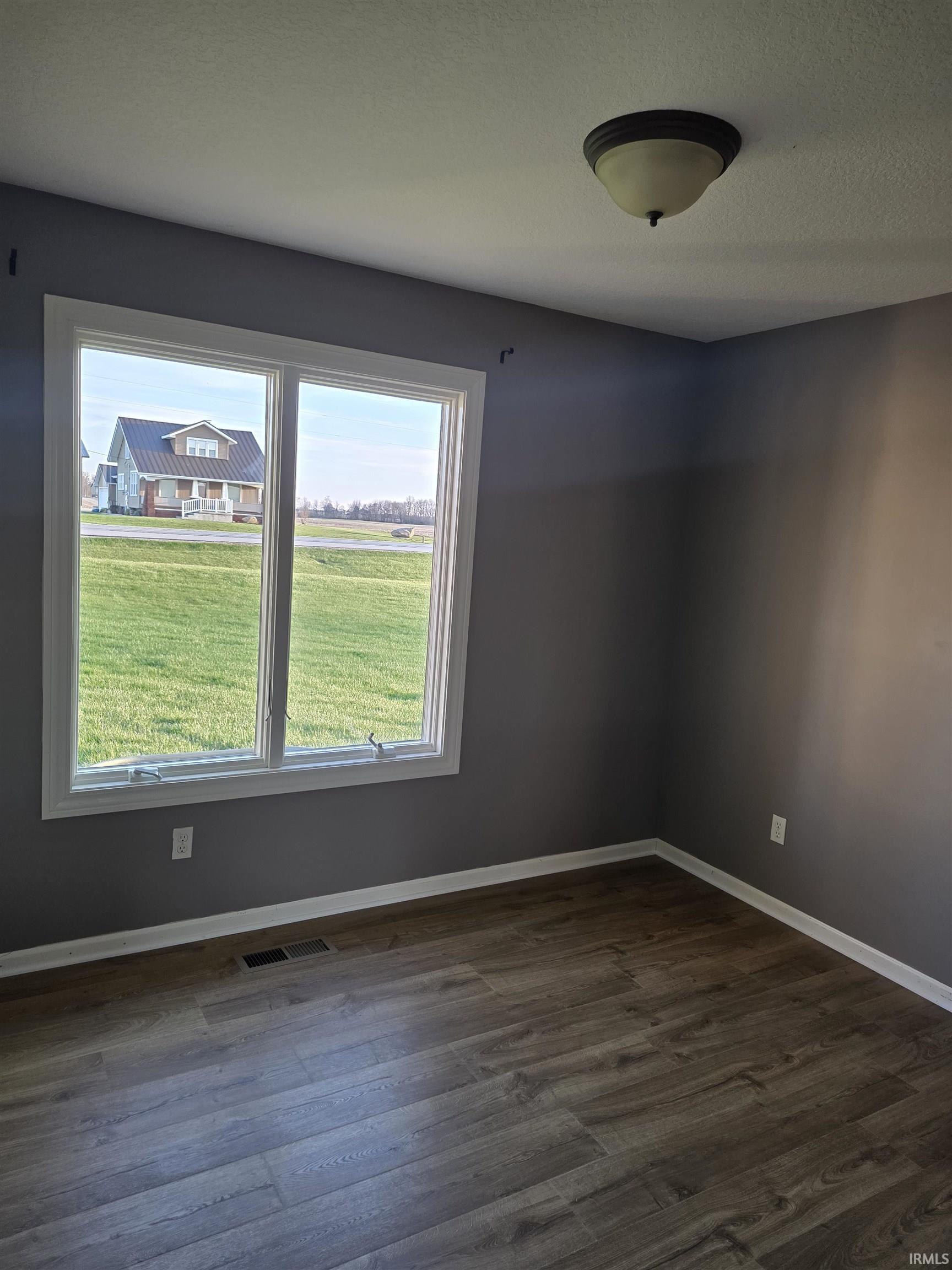 Unfurnished room with dark wood finished floors and a textured ceiling
