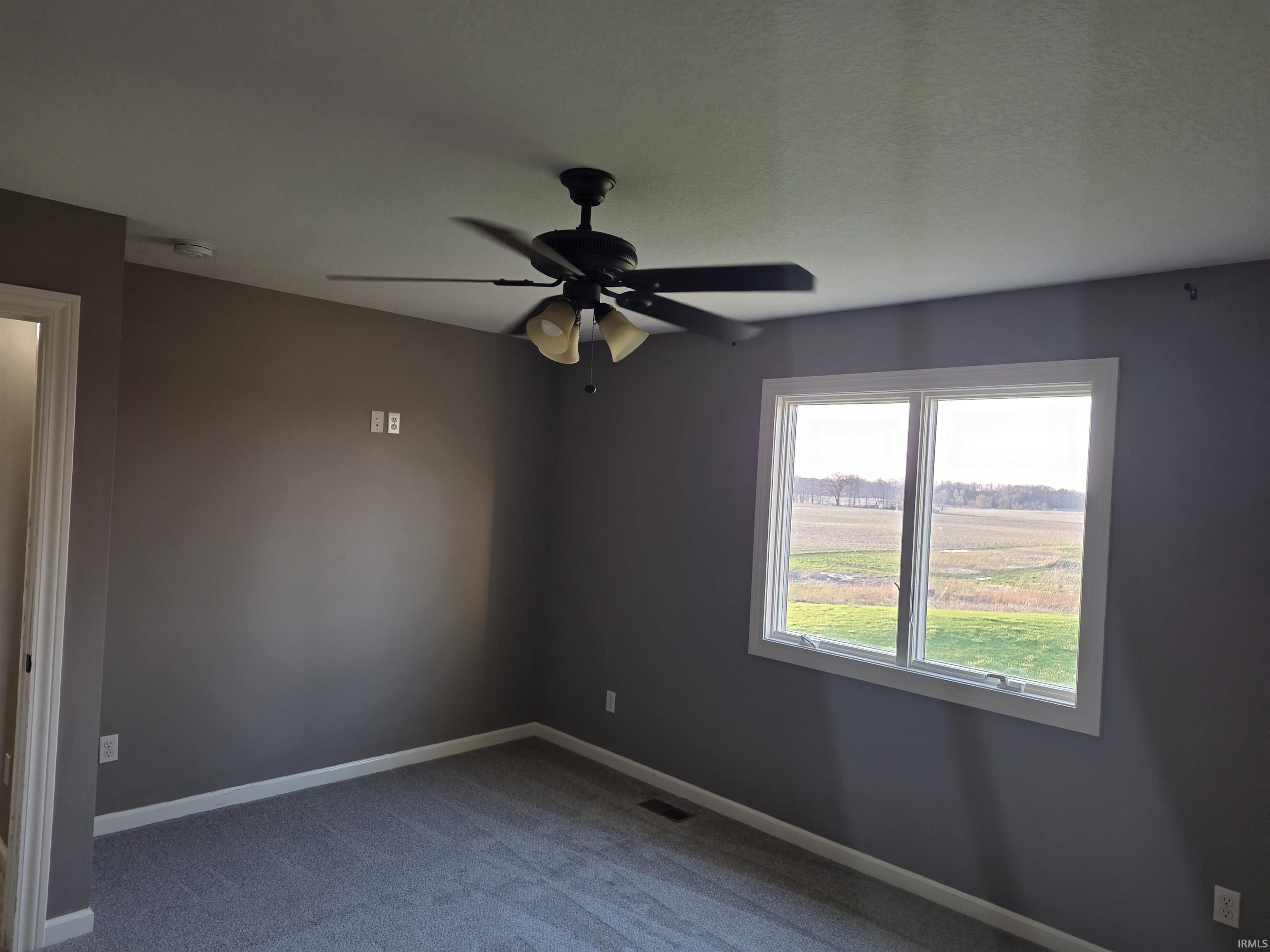 Empty room featuring a ceiling fan and light colored carpet