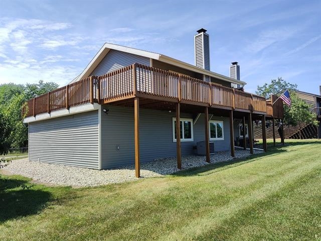 Back of property featuring a deck, a lawn, and a chimney