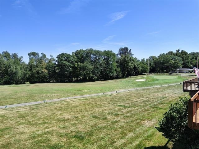 View of grassy yard featuring view of golf course and view of scattered trees