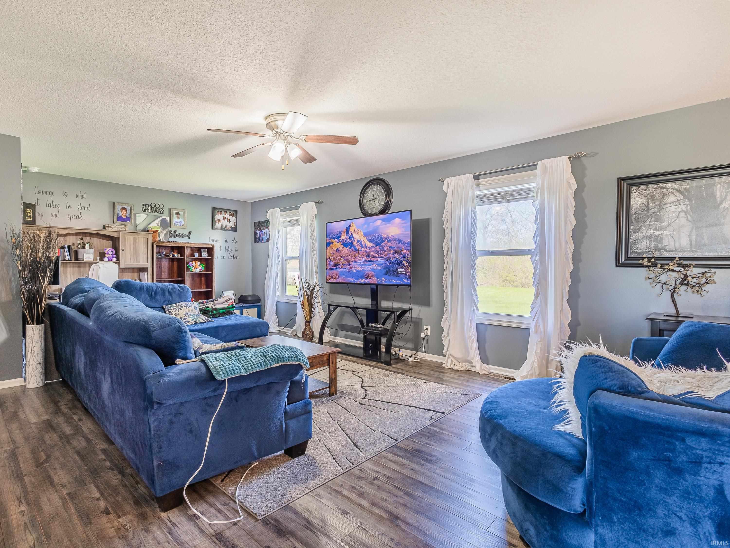 Living area featuring wood finished floors, a ceiling fan, and a textured ceiling
