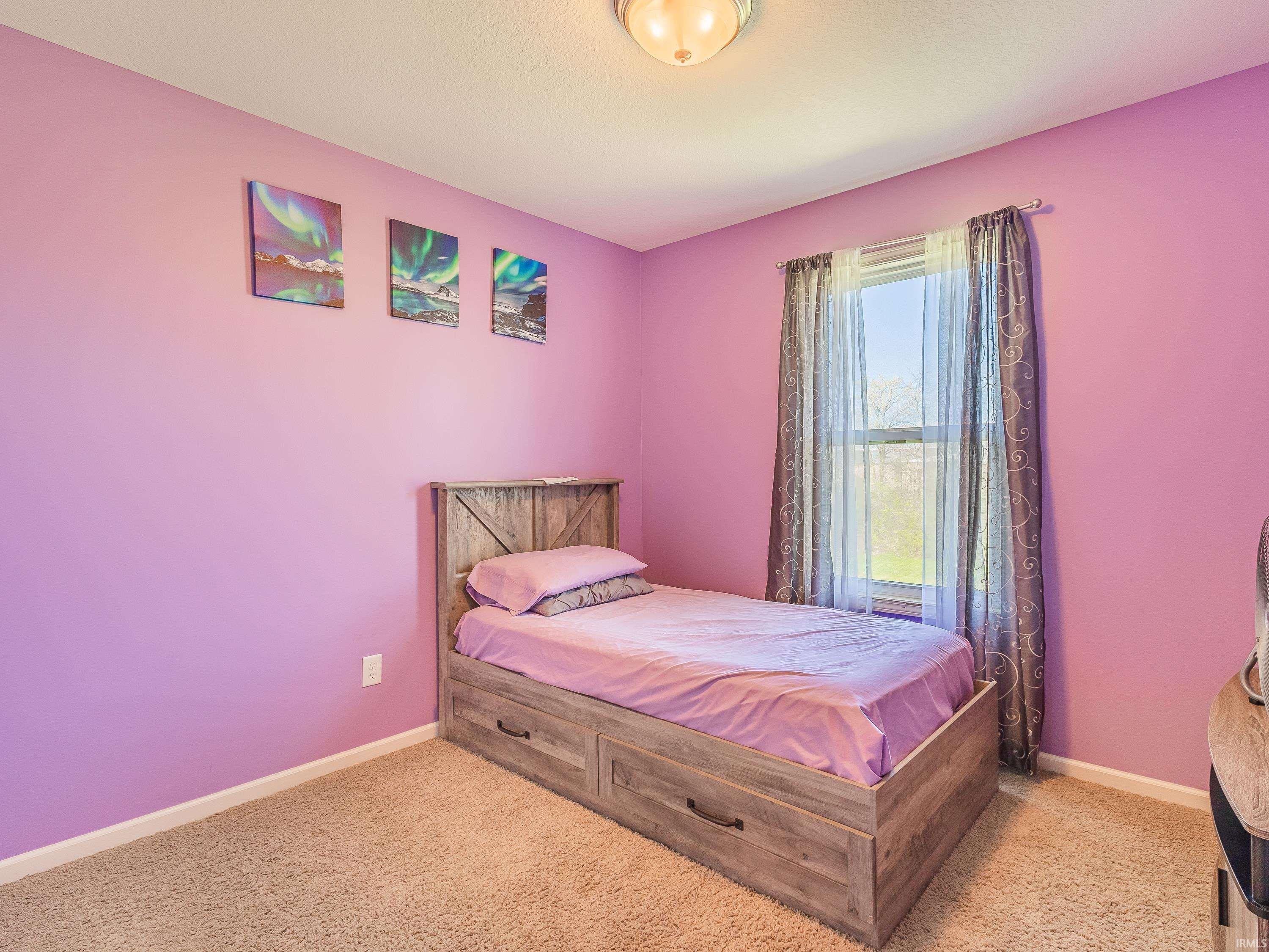 Bedroom featuring light carpet and baseboards