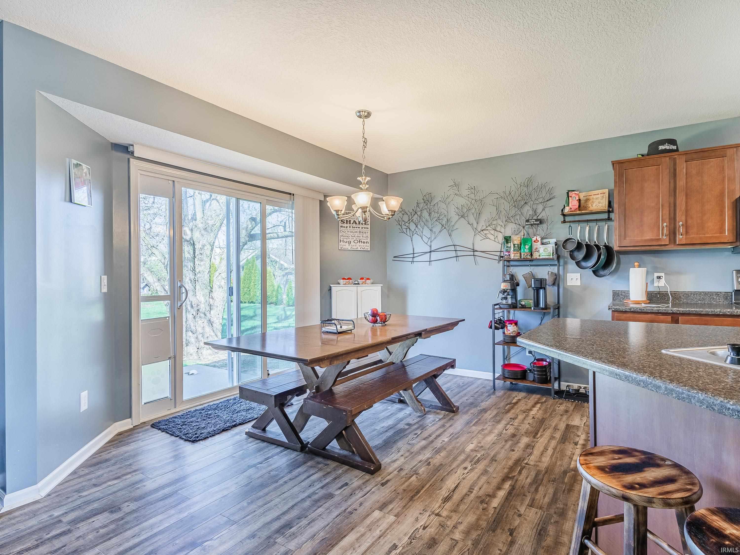 Dining space featuring dark wood finished floors, suspended lighting, and a textured ceiling