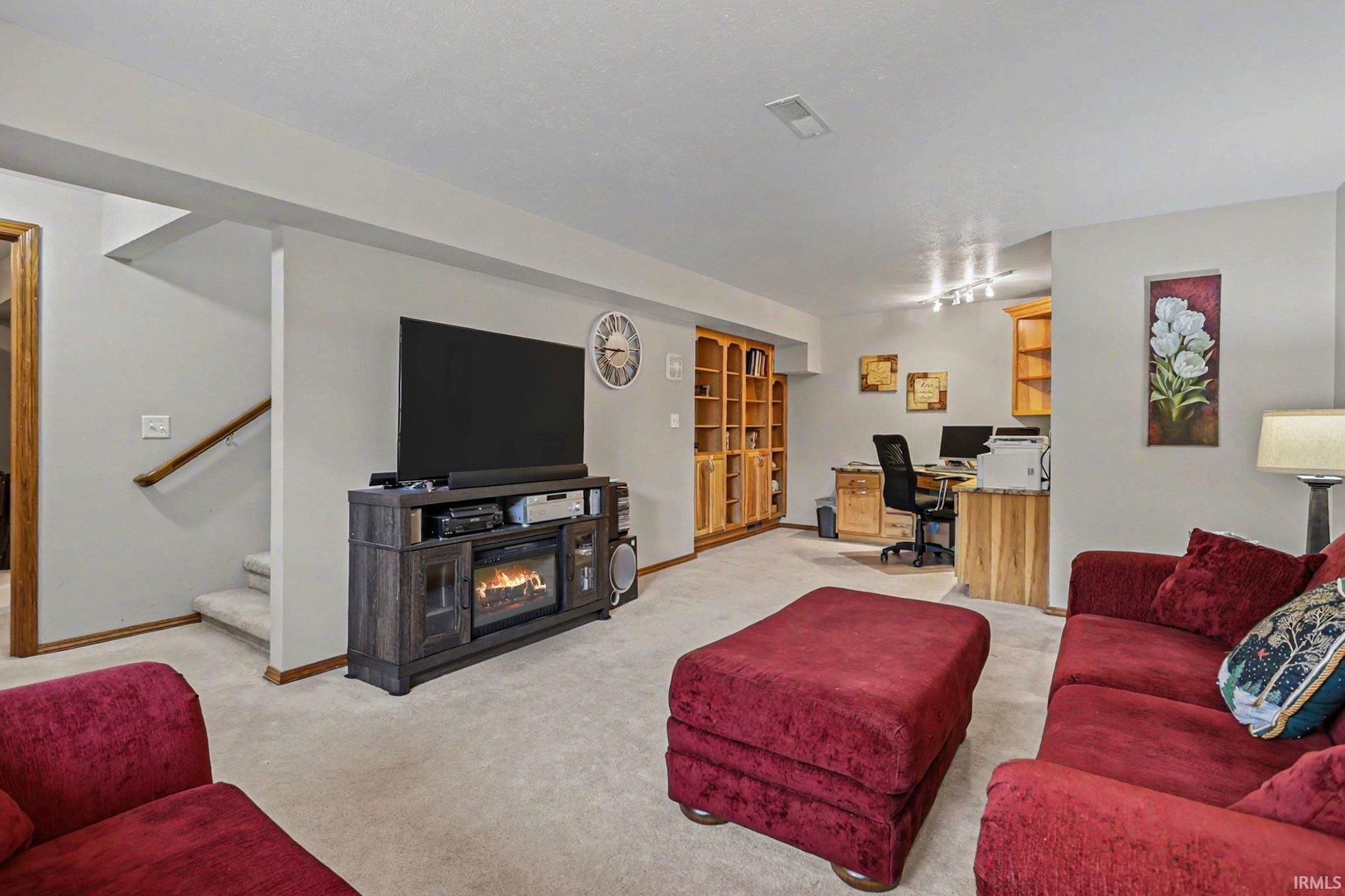 Living area featuring a desk, light carpet, and a glass covered fireplace