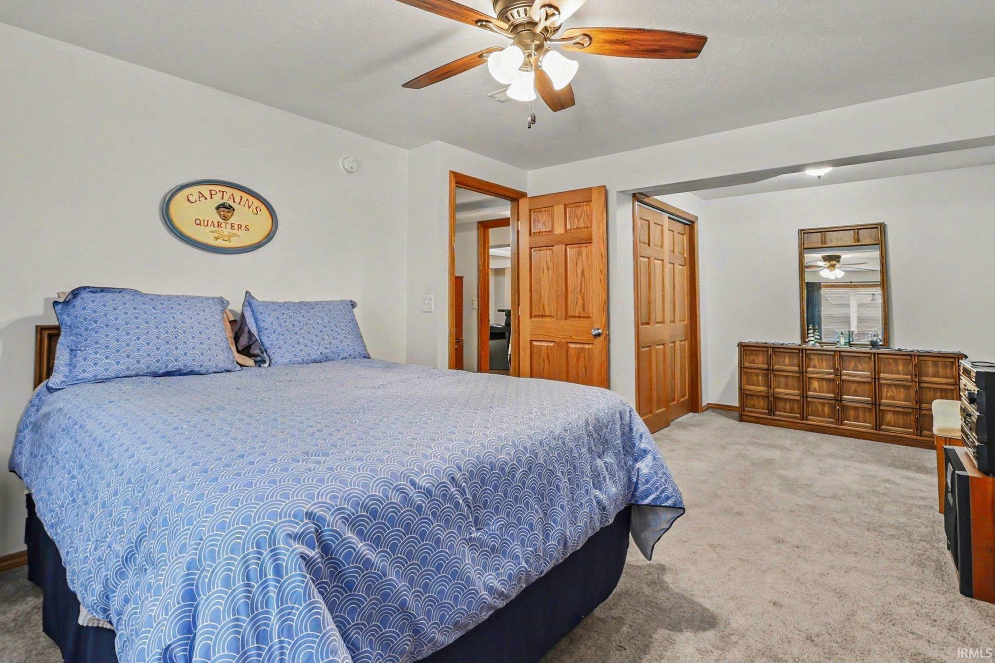 Bedroom with light carpet, ceiling fan, and a closet