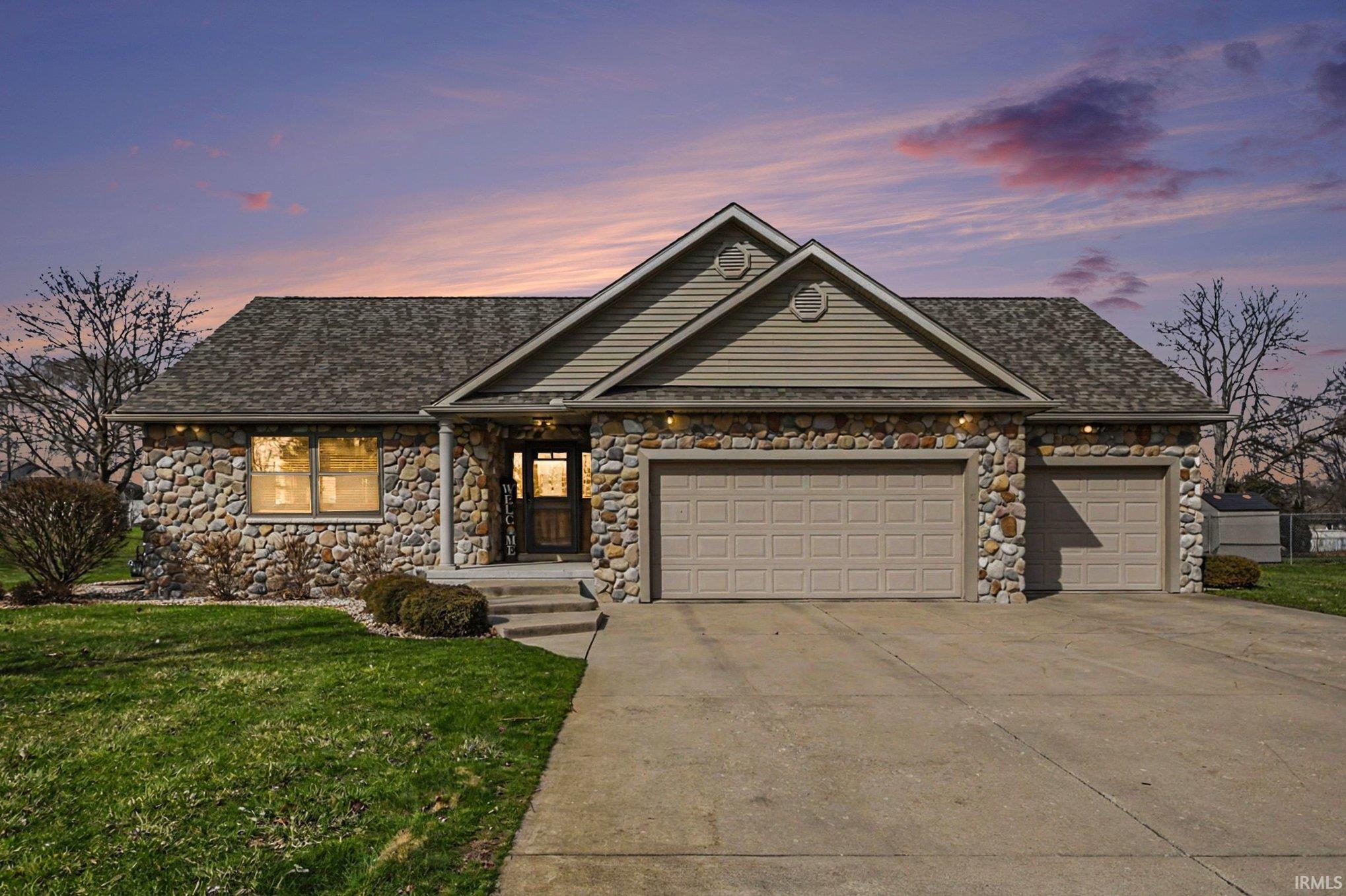 View of front of property with an attached garage, stone siding, and driveway