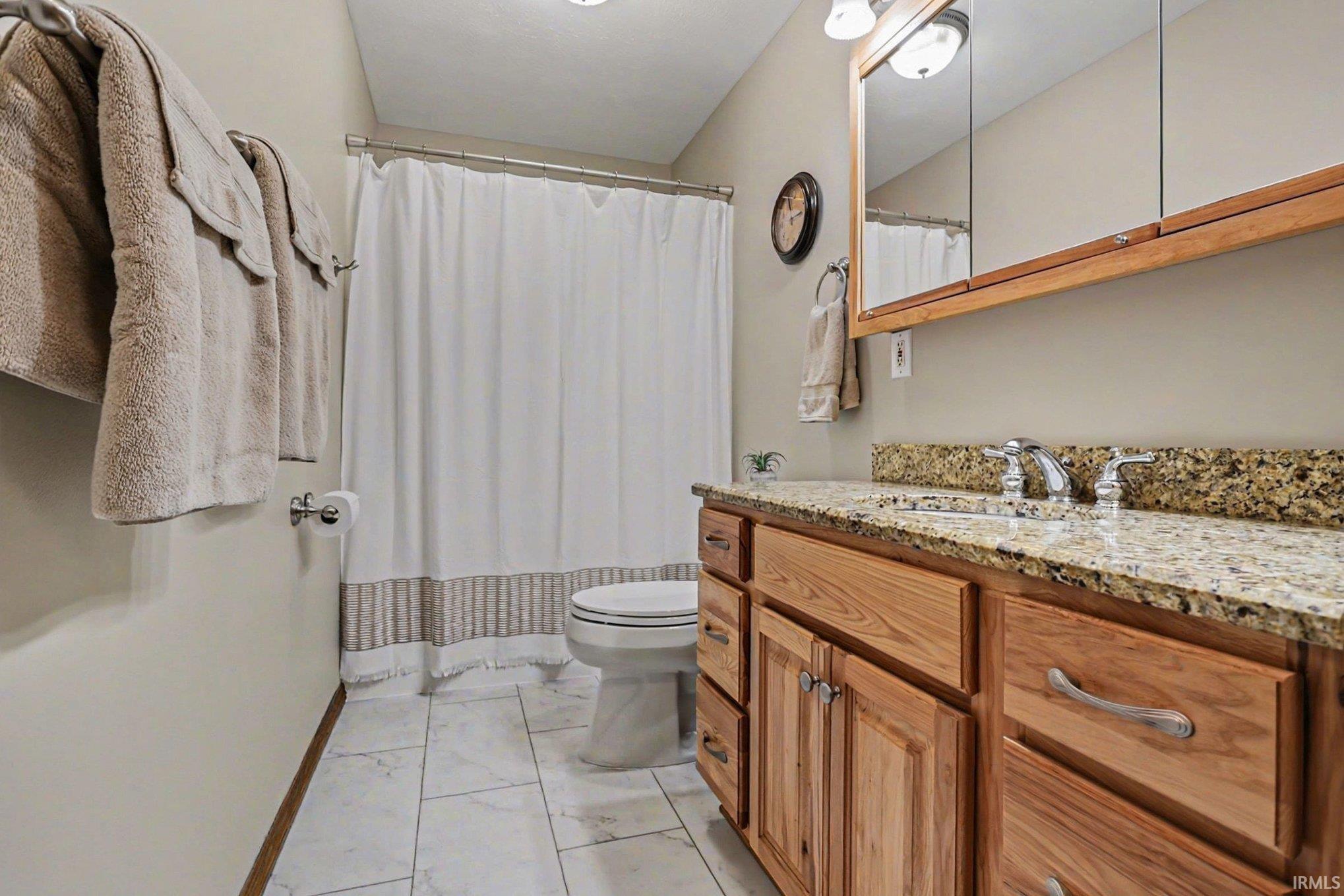 Full bath with vanity, a shower with shower curtain, and light marble finish floors