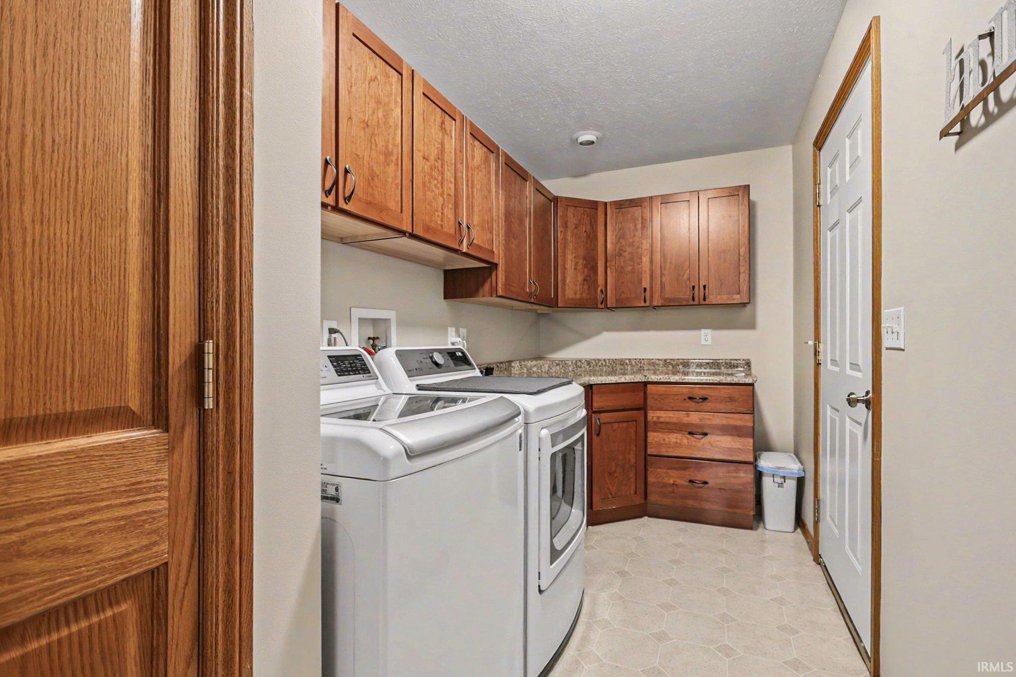 Laundry room with cabinet space, separate washer and dryer, and a textured ceiling