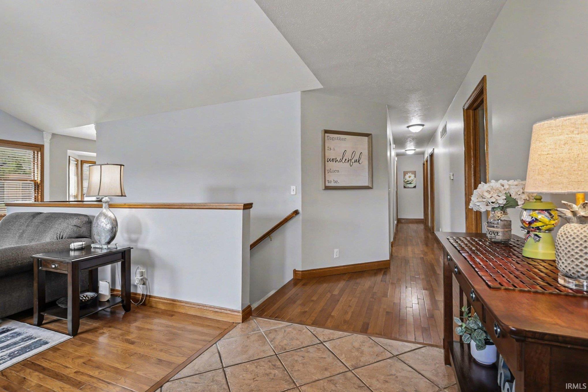 Hall featuring light tile patterned flooring, an upstairs landing, and lofted ceiling
