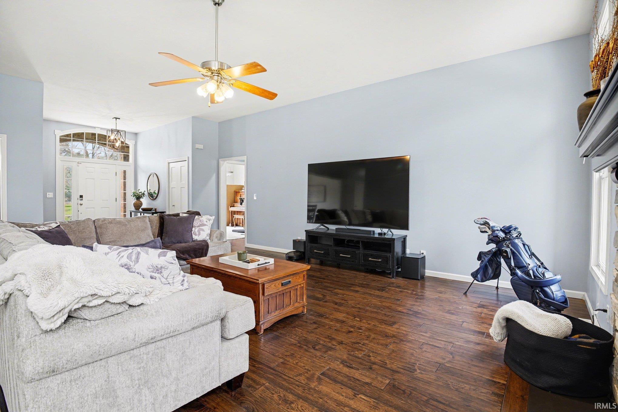 Living area featuring dark wood-style flooring, a ceiling fan, suspended lighting, and lofted ceiling