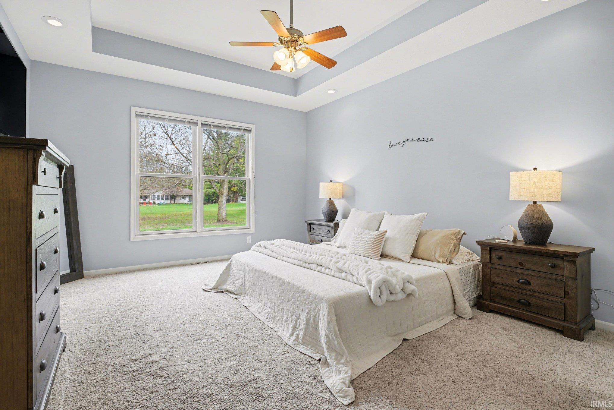 Bedroom with light carpet, a tray ceiling, a ceiling fan, and recessed lighting