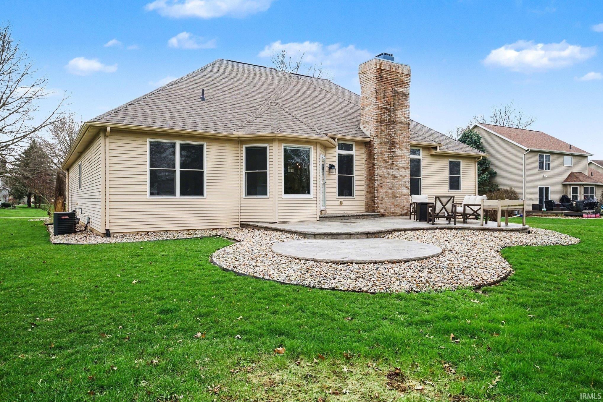 Back of house with a patio, a yard, a shingled roof, and a chimney