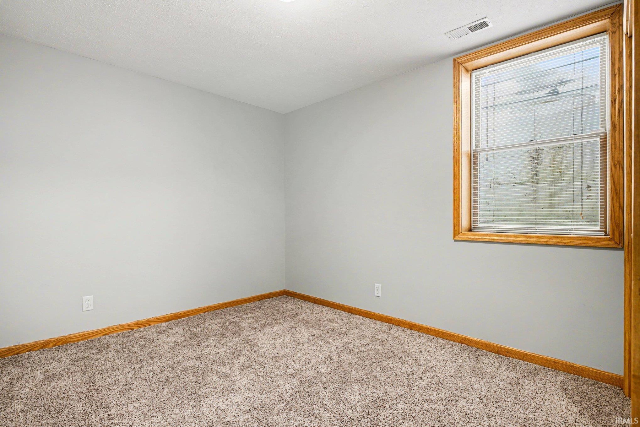 Empty room with light carpet and baseboards