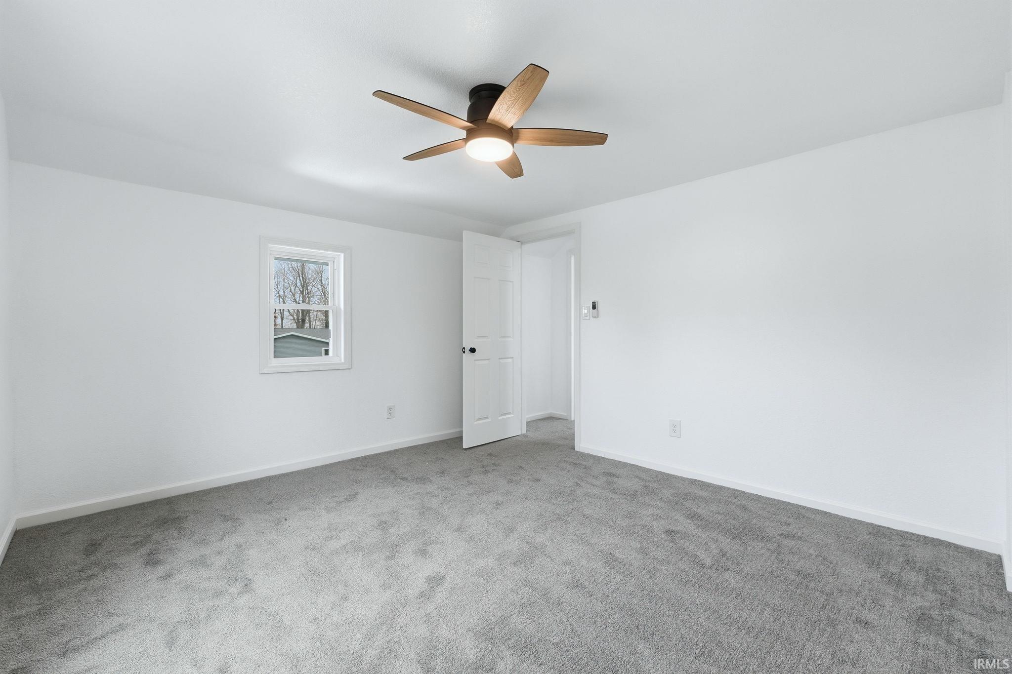 Carpeted spare room with baseboards and a ceiling fan