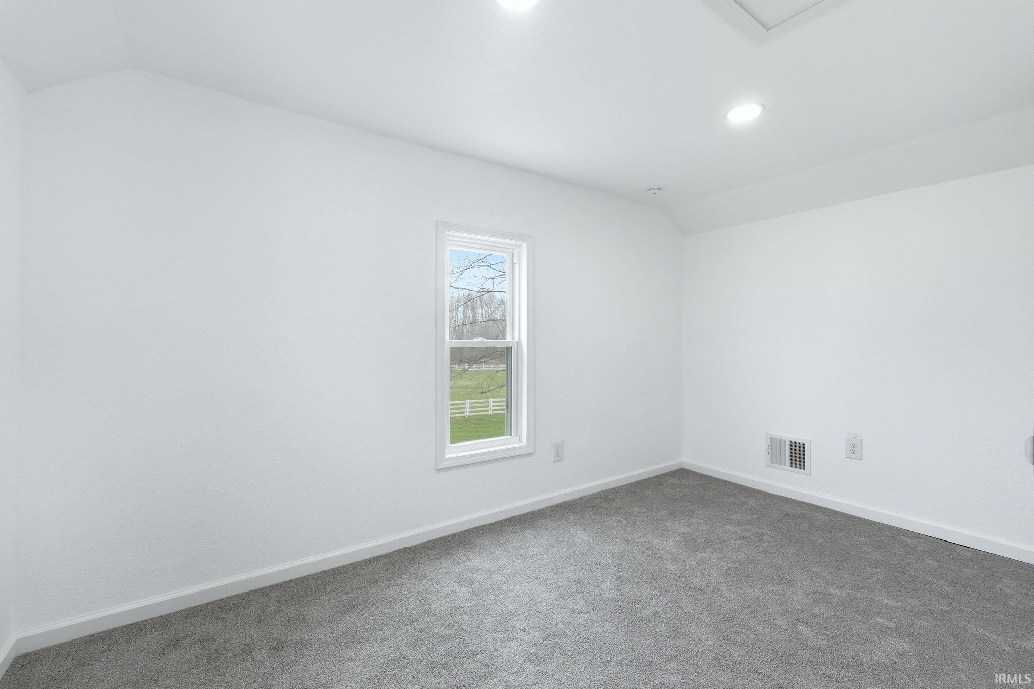 Spare room featuring lofted ceiling, dark colored carpet, and recessed lighting