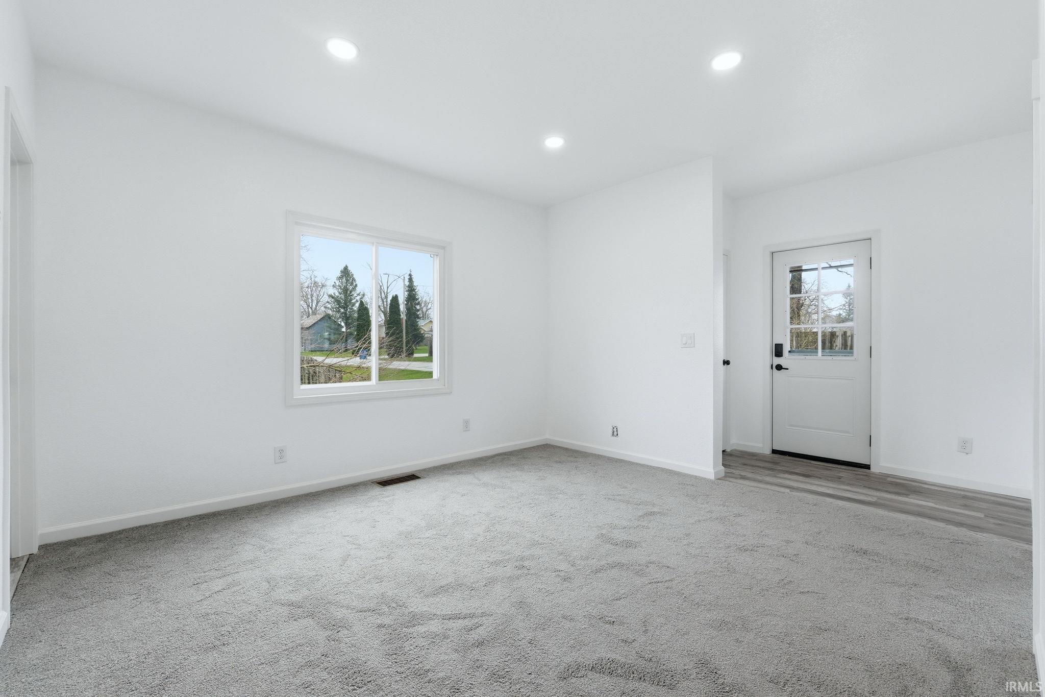 Unfurnished room featuring light colored carpet, recessed lighting, and healthy amount of natural light