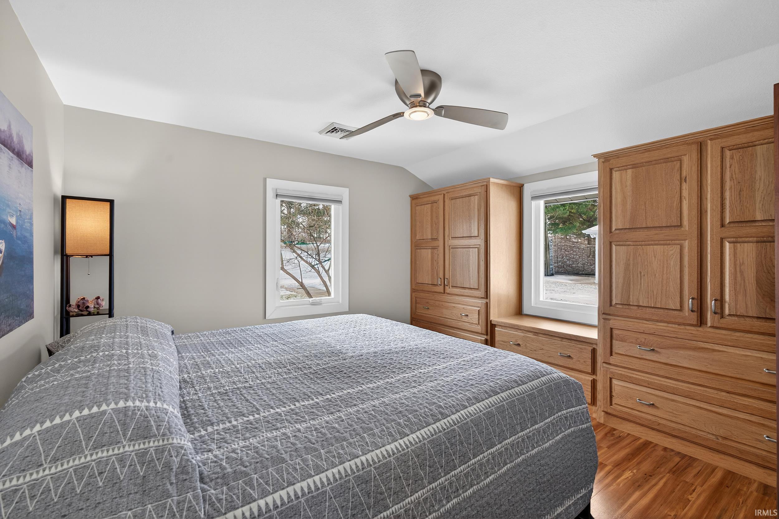 Bedroom with vaulted ceiling, wood finished floors, and a ceiling fan