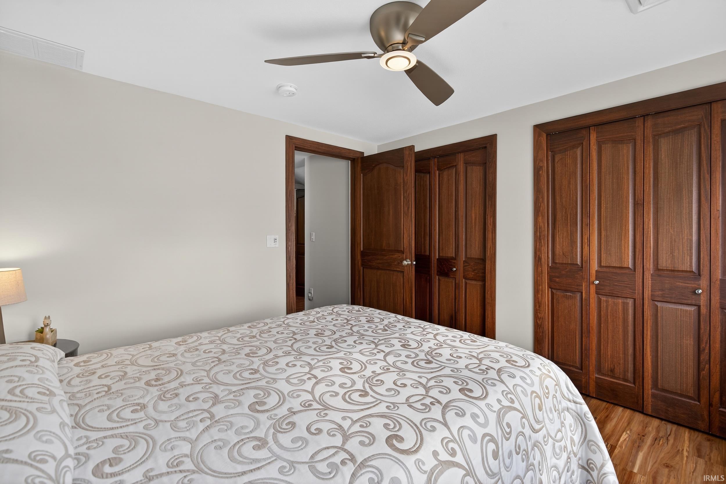 Bedroom featuring two closets, light wood-style floors, and a ceiling fan