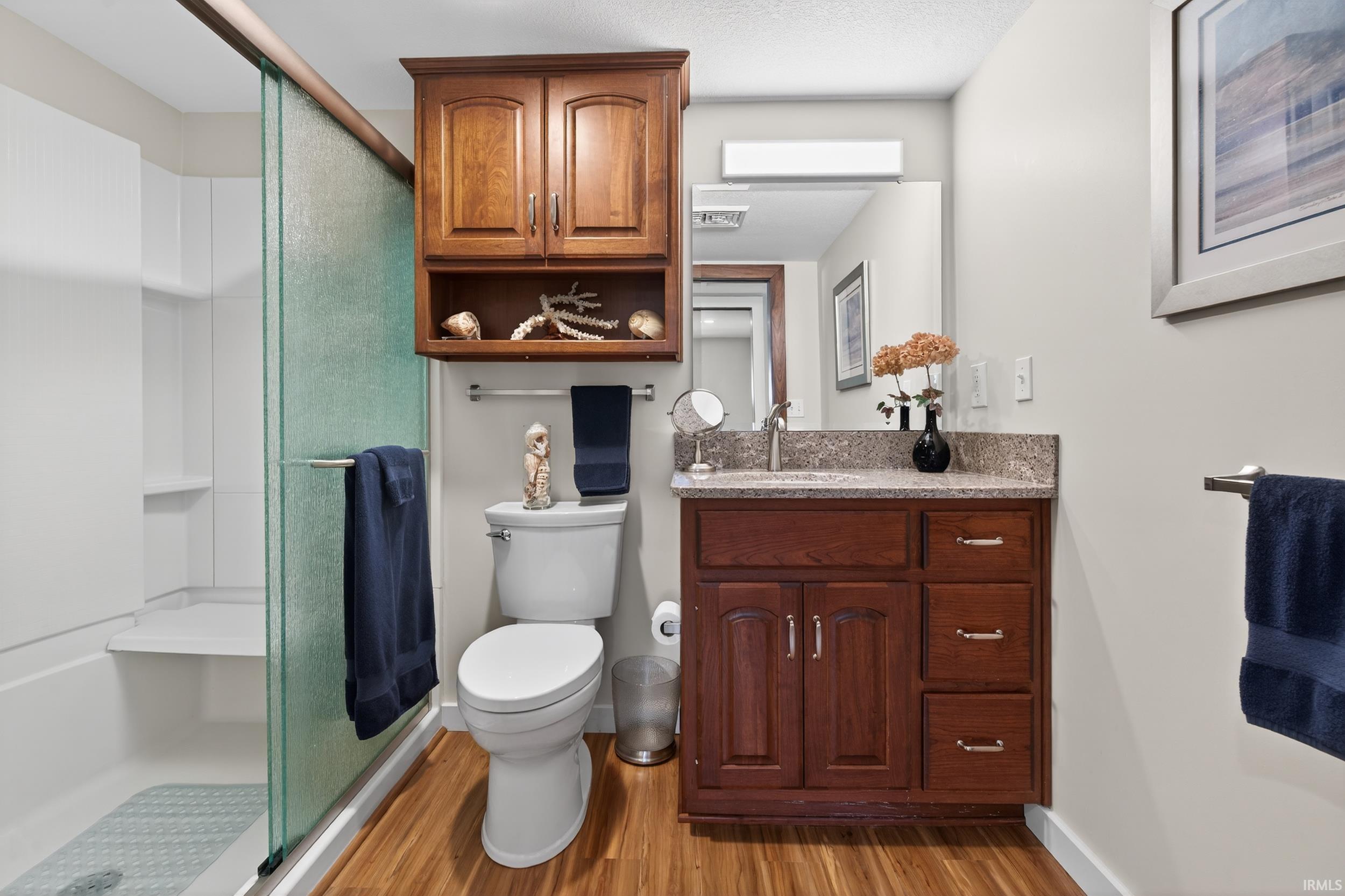 Full bath featuring vanity, a shower stall, and light wood-type flooring