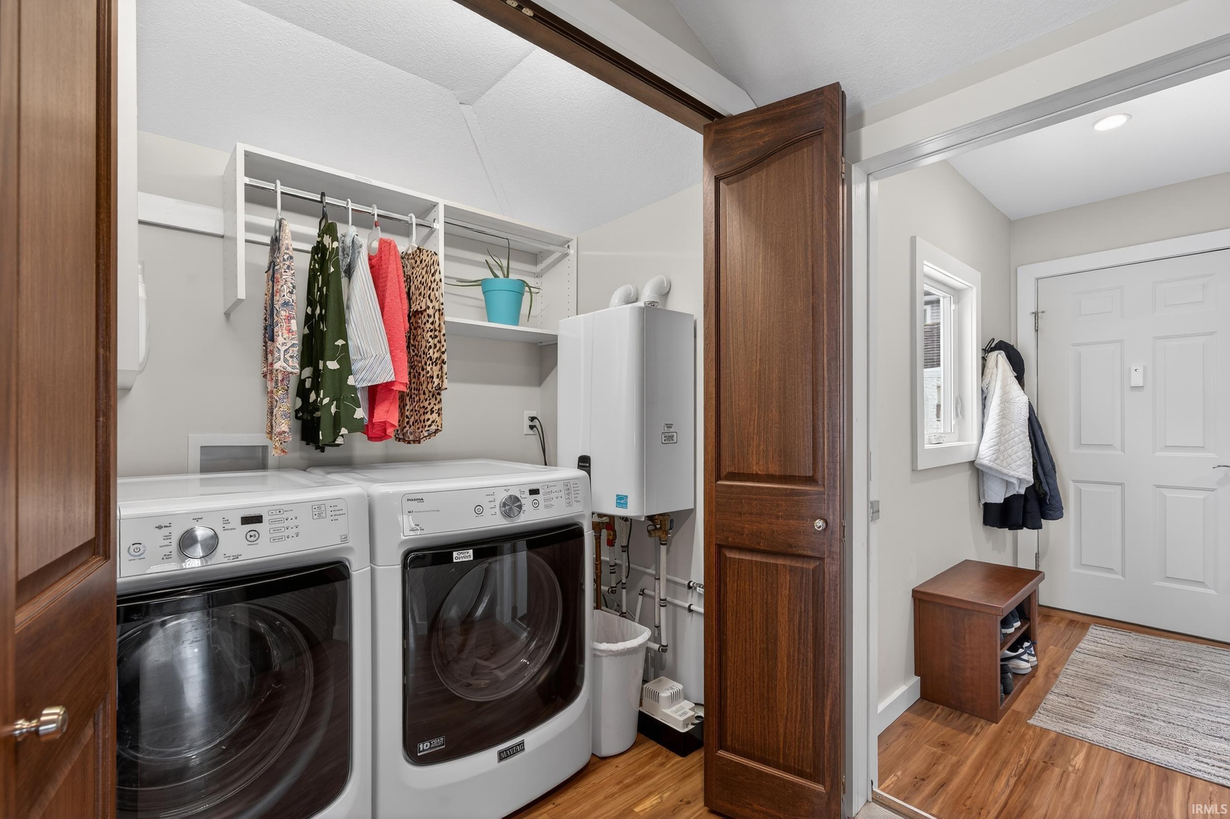Laundry area with water heater, light wood-type flooring, and washer and dryer