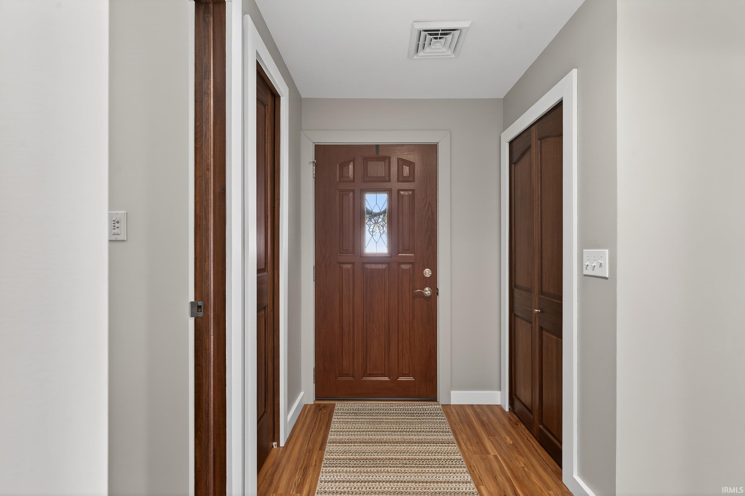 Doorway with wood finished floors and baseboards