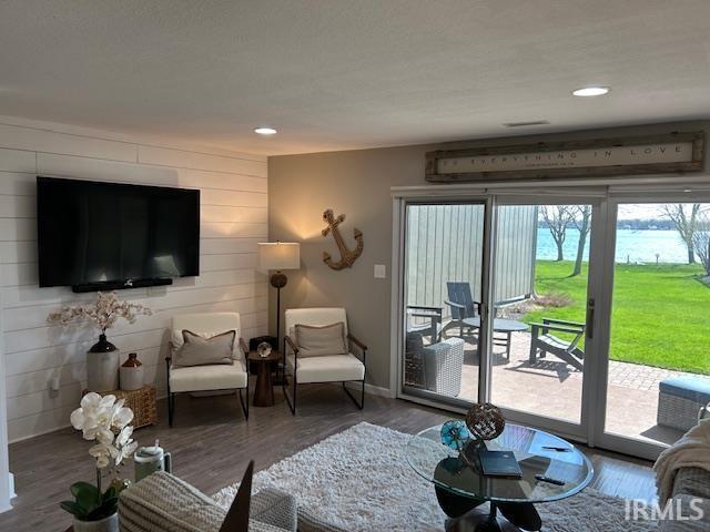 Living room featuring wood finished floors, an accent wall, wood walls, and recessed lighting