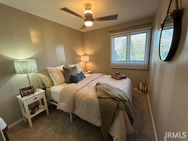 Bedroom featuring a ceiling fan and dark carpet
