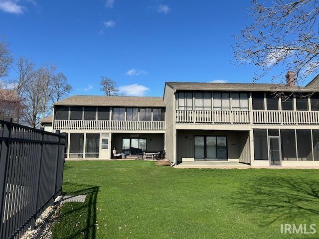 Back of property with a sunroom, a patio area, and a chimney