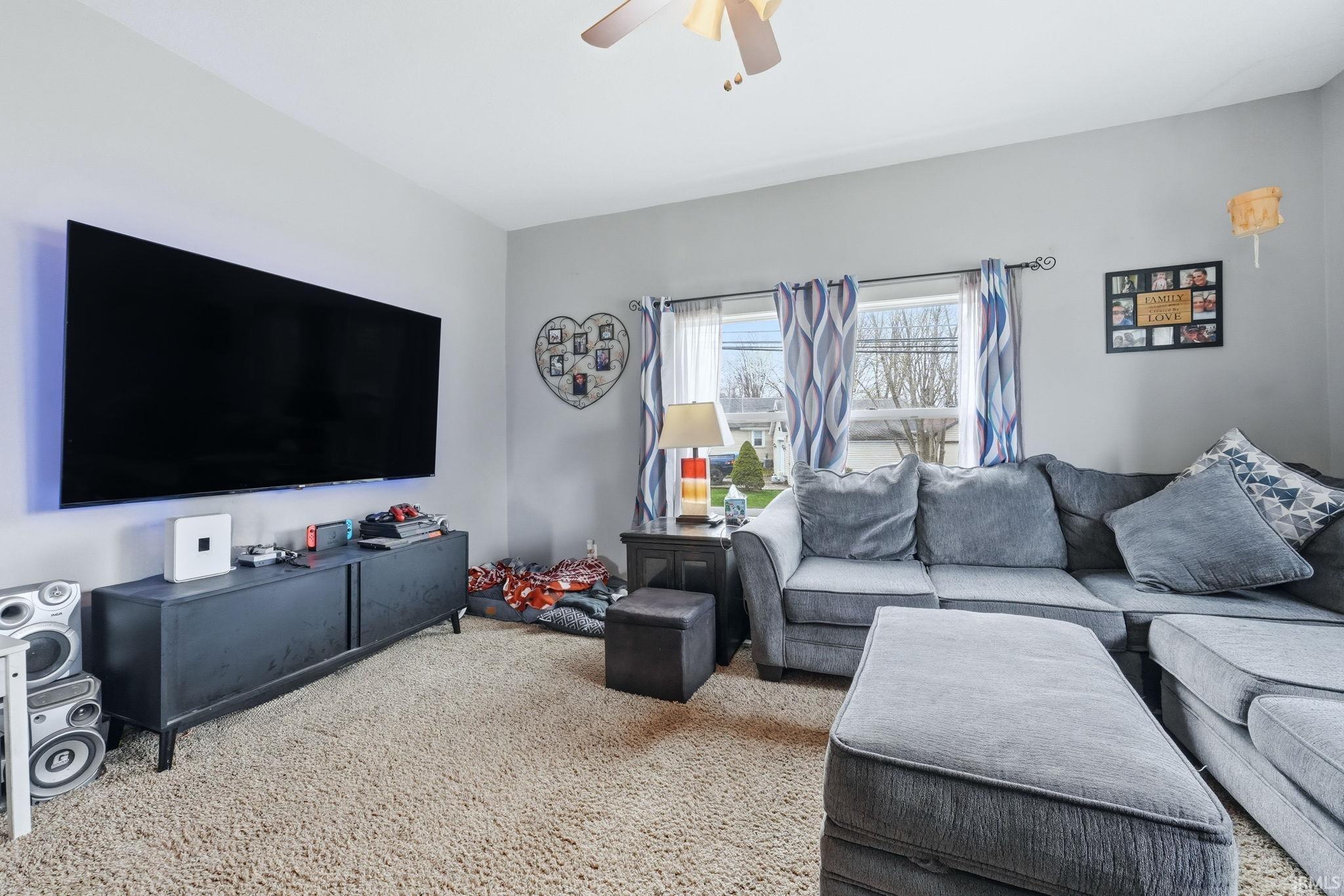 Carpeted living room featuring ceiling fan