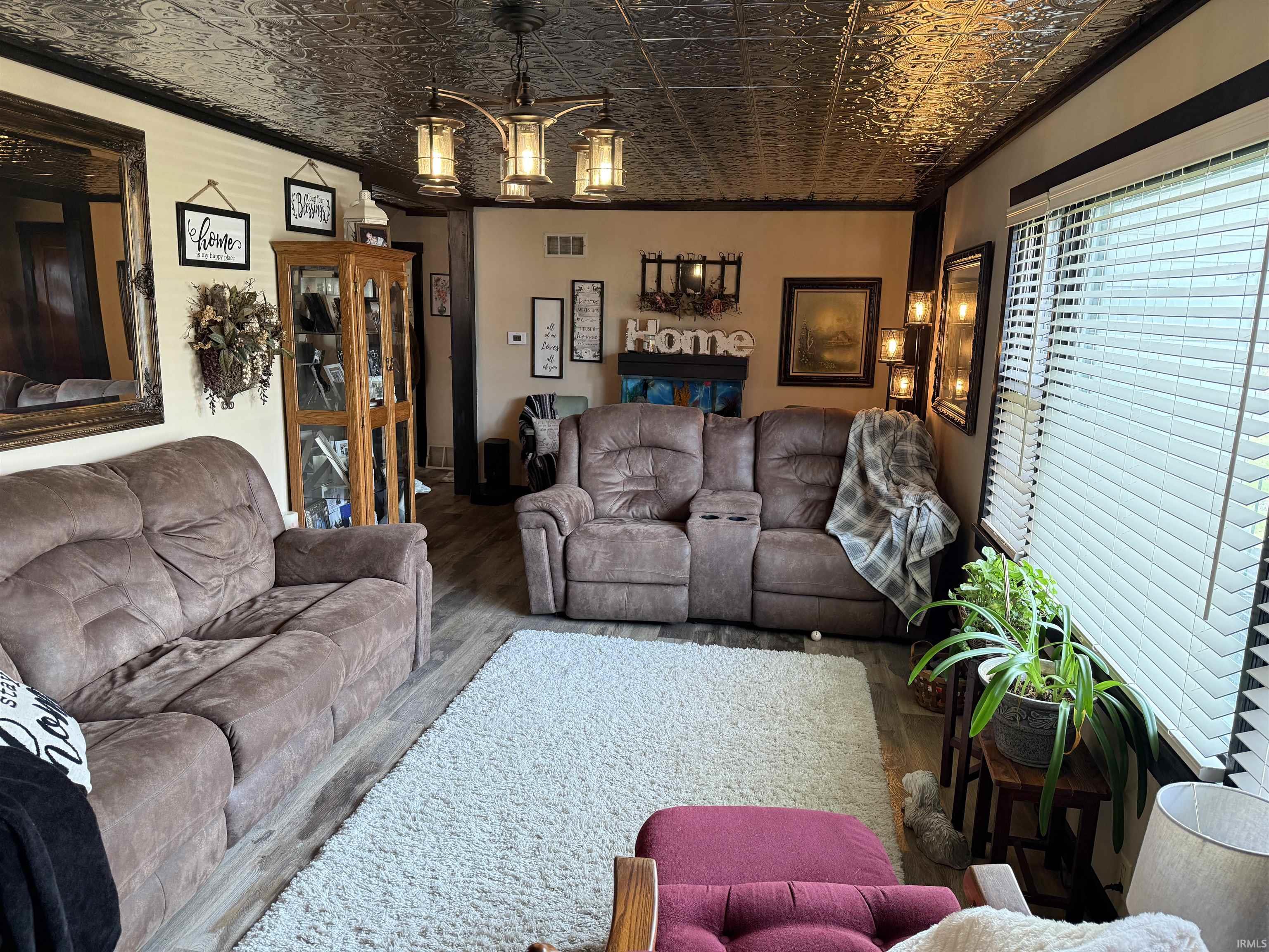 Living area featuring an ornate ceiling, hanging lights, wood finished floors, and crown molding