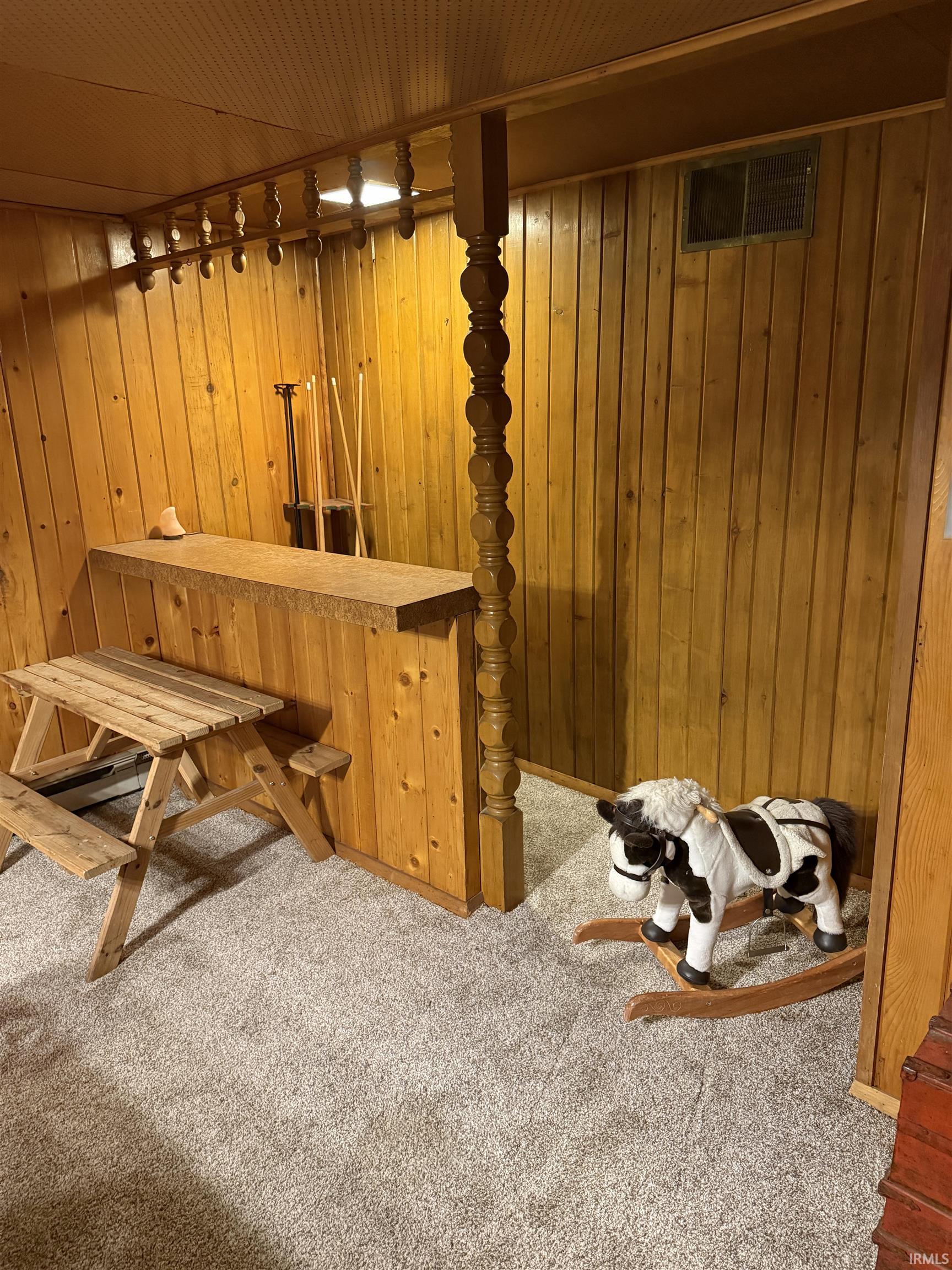 Basement with carpet, wooden ceiling, and wooden walls