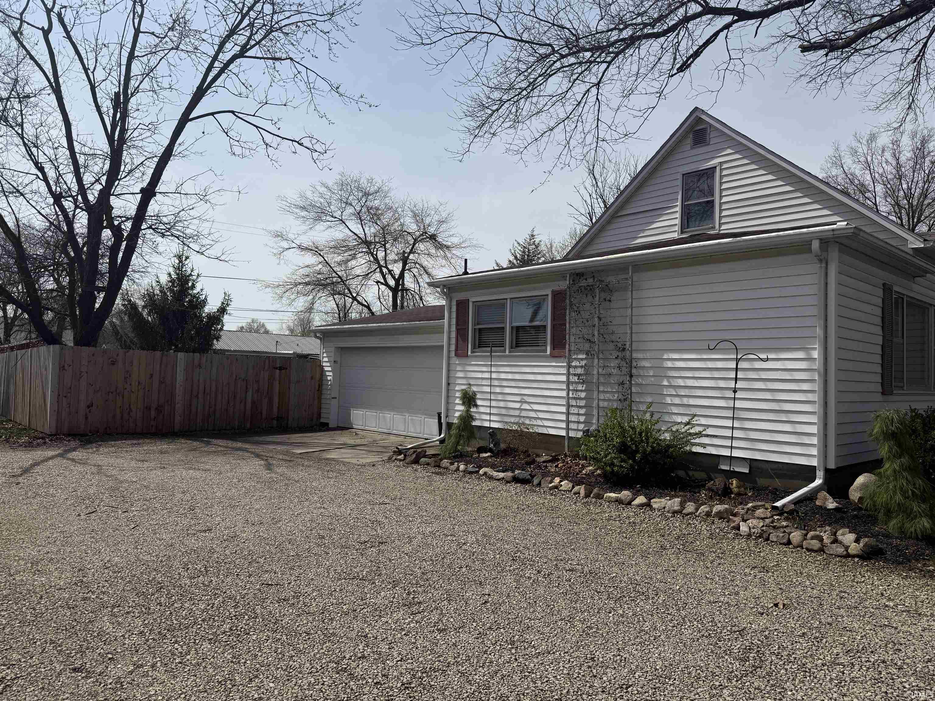 View of side of home featuring gravel driveway and an attached garage