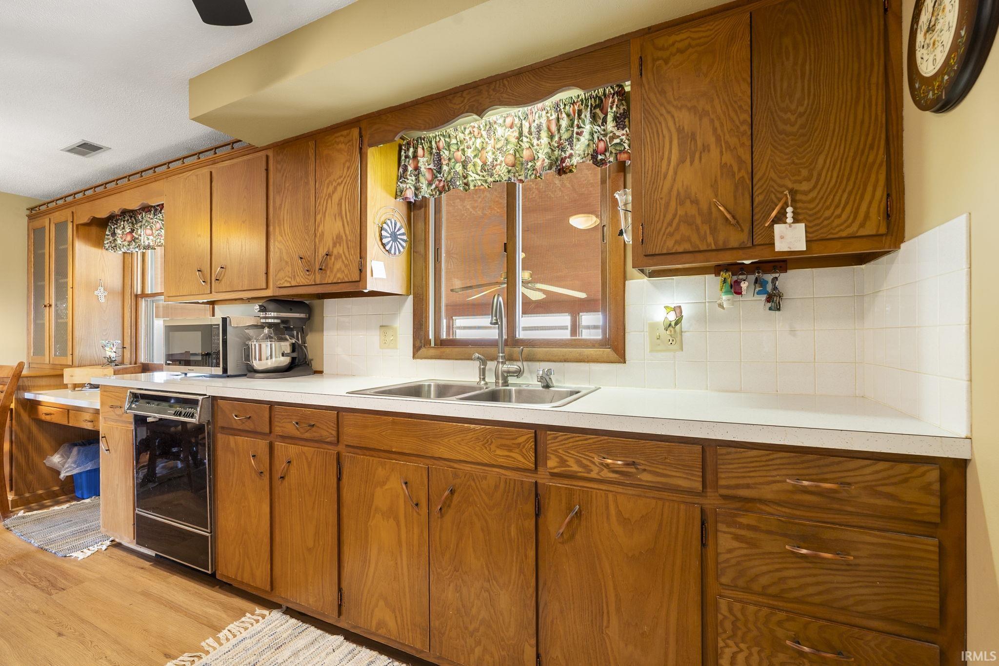 Kitchen with ceiling fan, wood finish cabinets, light countertops, and tasteful backsplash