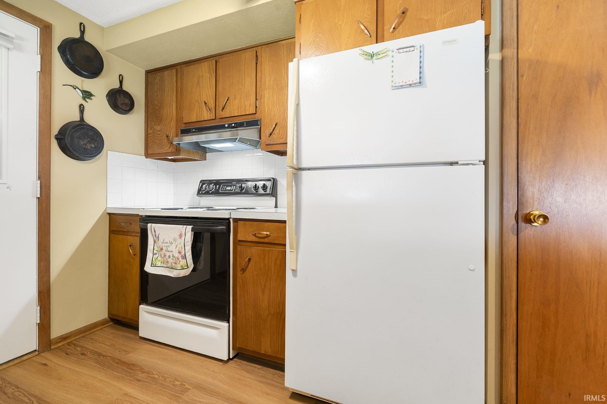 Kitchen featuring wood finish cabinetry, freestanding refrigerator, electric range, and light countertops