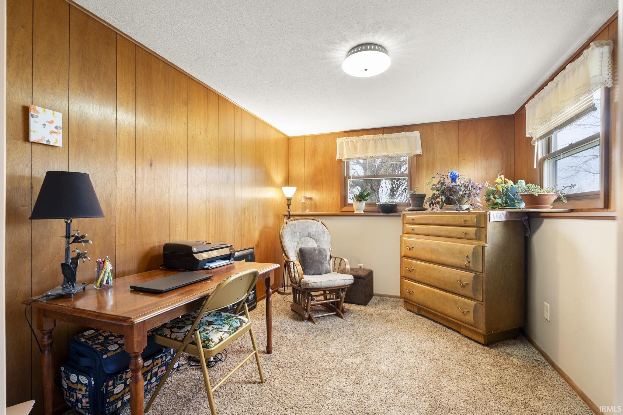 Office space featuring light carpet and wooden walls