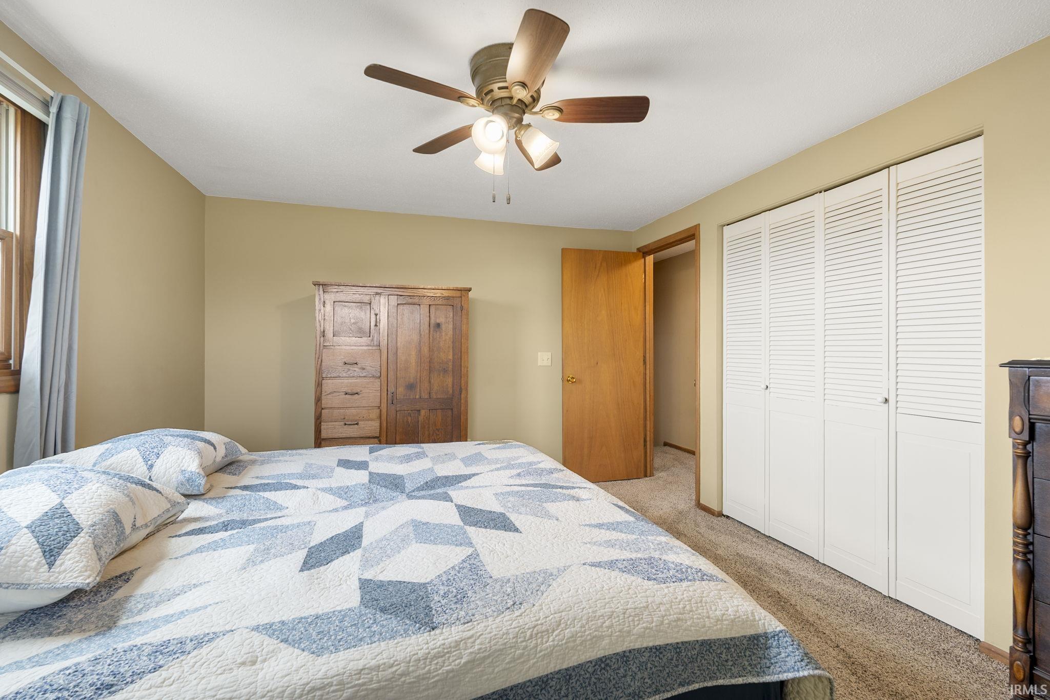Bedroom with ceiling fan, carpet flooring, and a closet