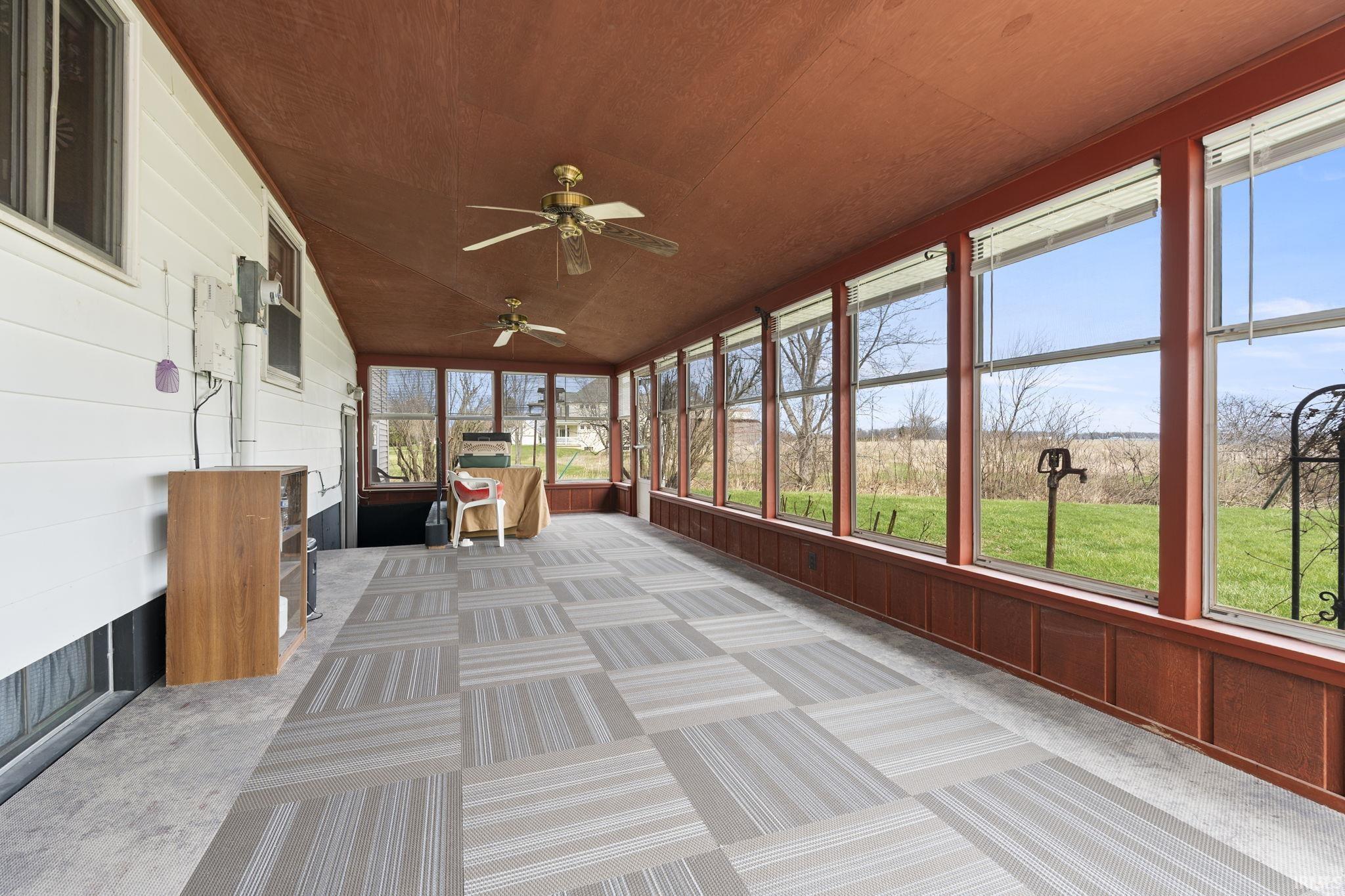Unfurnished sunroom featuring ceiling fan and vaulted ceiling