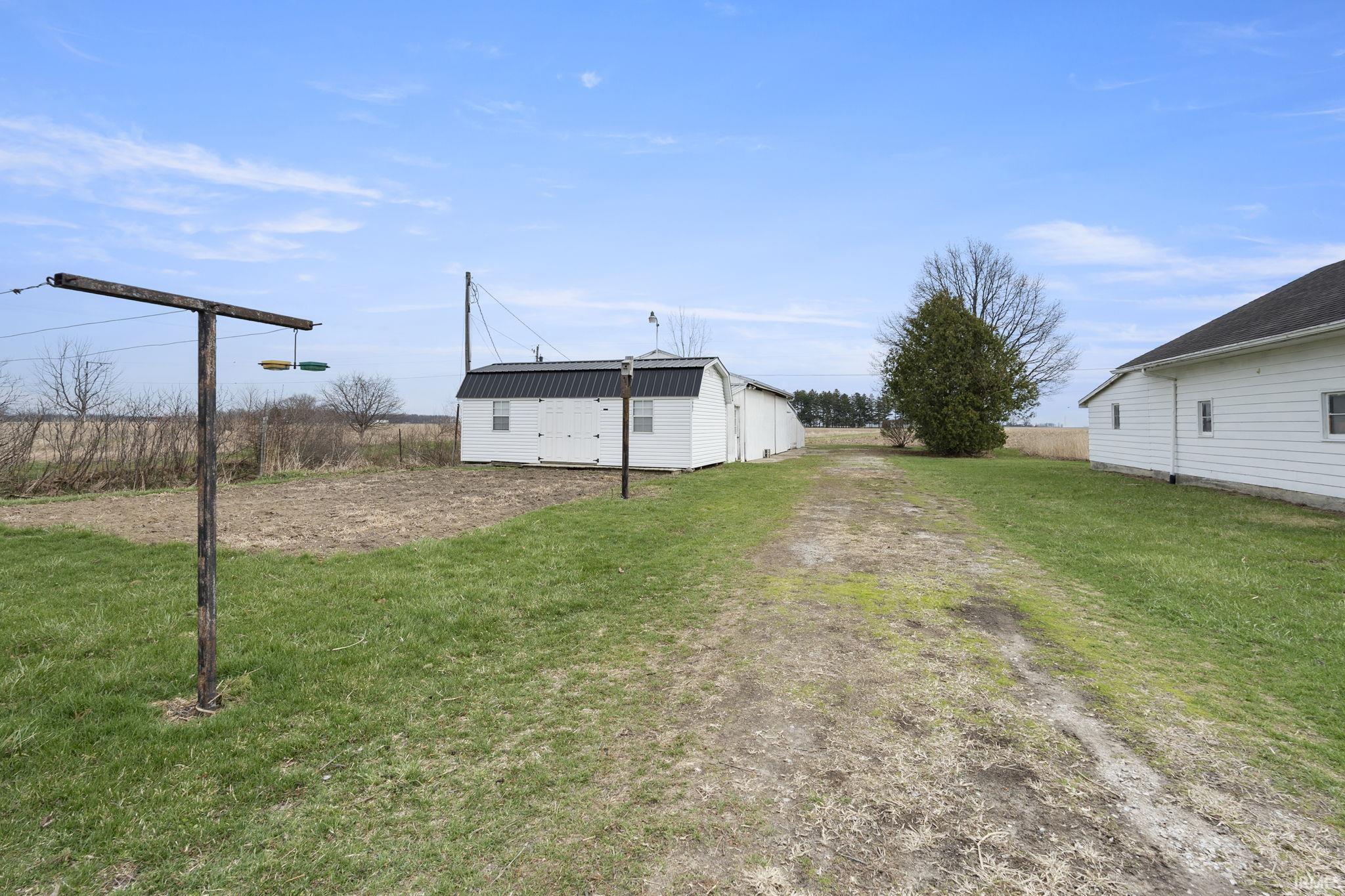 View of green lawn featuring an outdoor structure and driveway