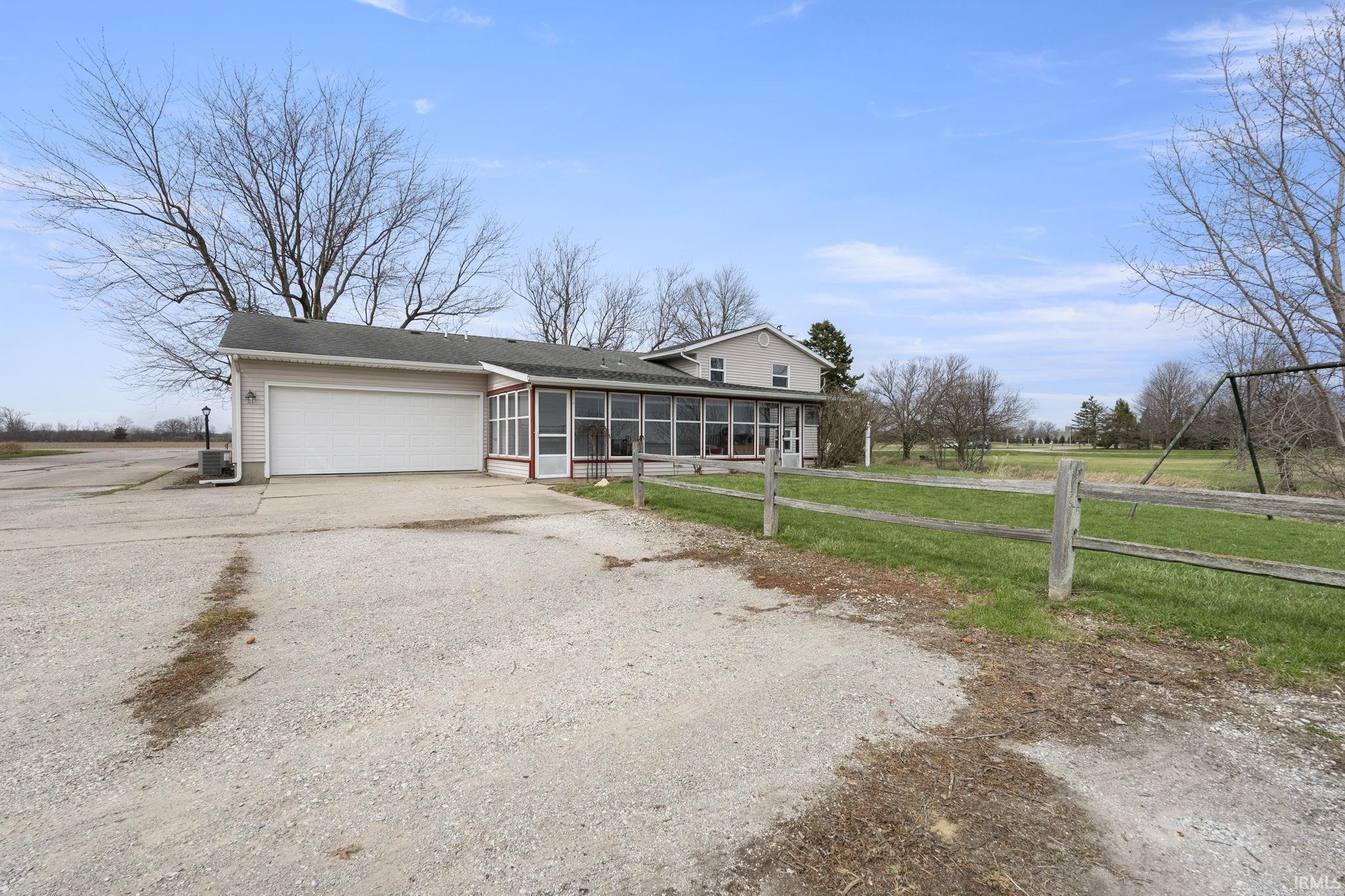 View of front of house with a sunroom, driveway, an attached garage, and a front yard