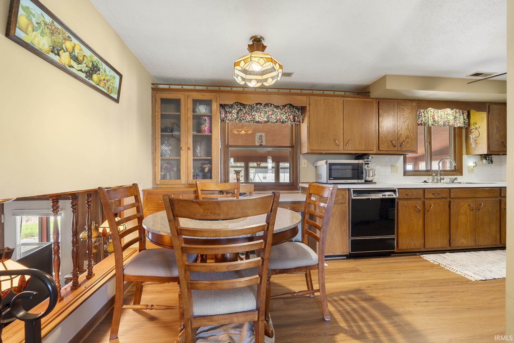 Kitchen with light countertops, wood finish cabinets, light wood-style floors, and black dishwasher,