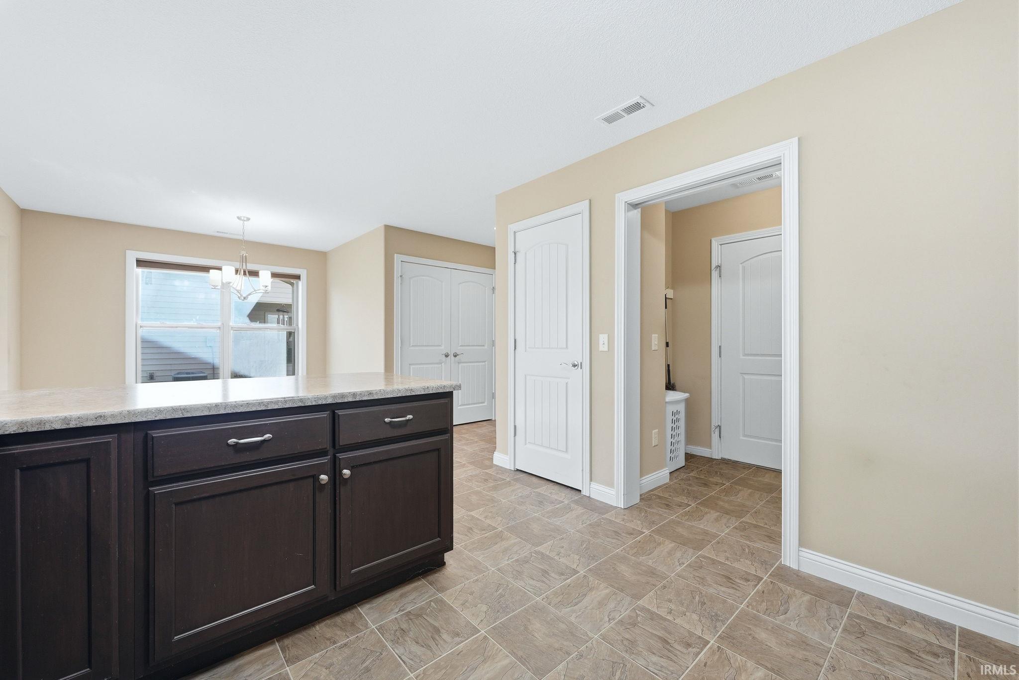 Kitchen with dark wood finish cabinetry, stone finish floors, and suspended lighting