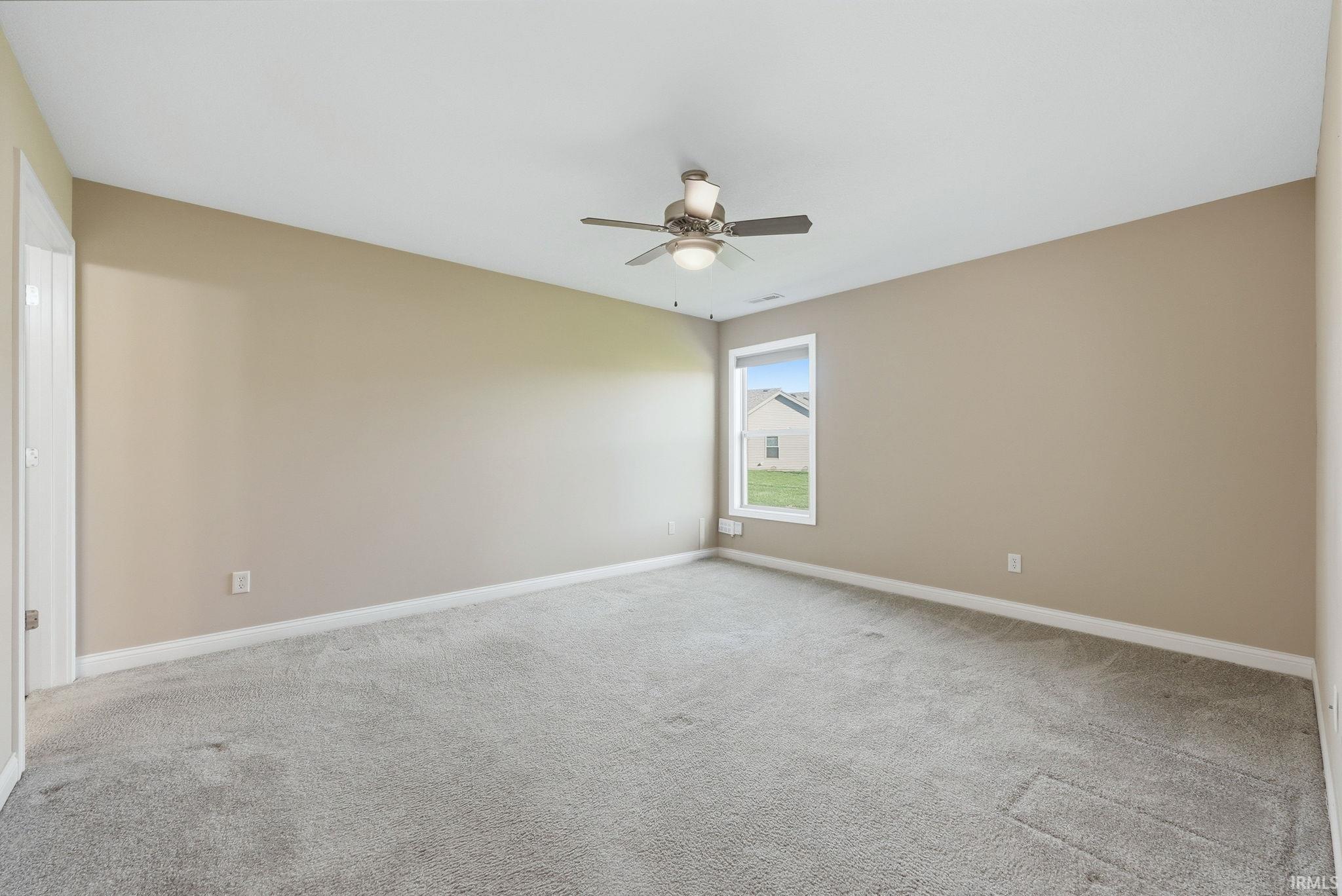 Empty room with light carpet and ceiling fan