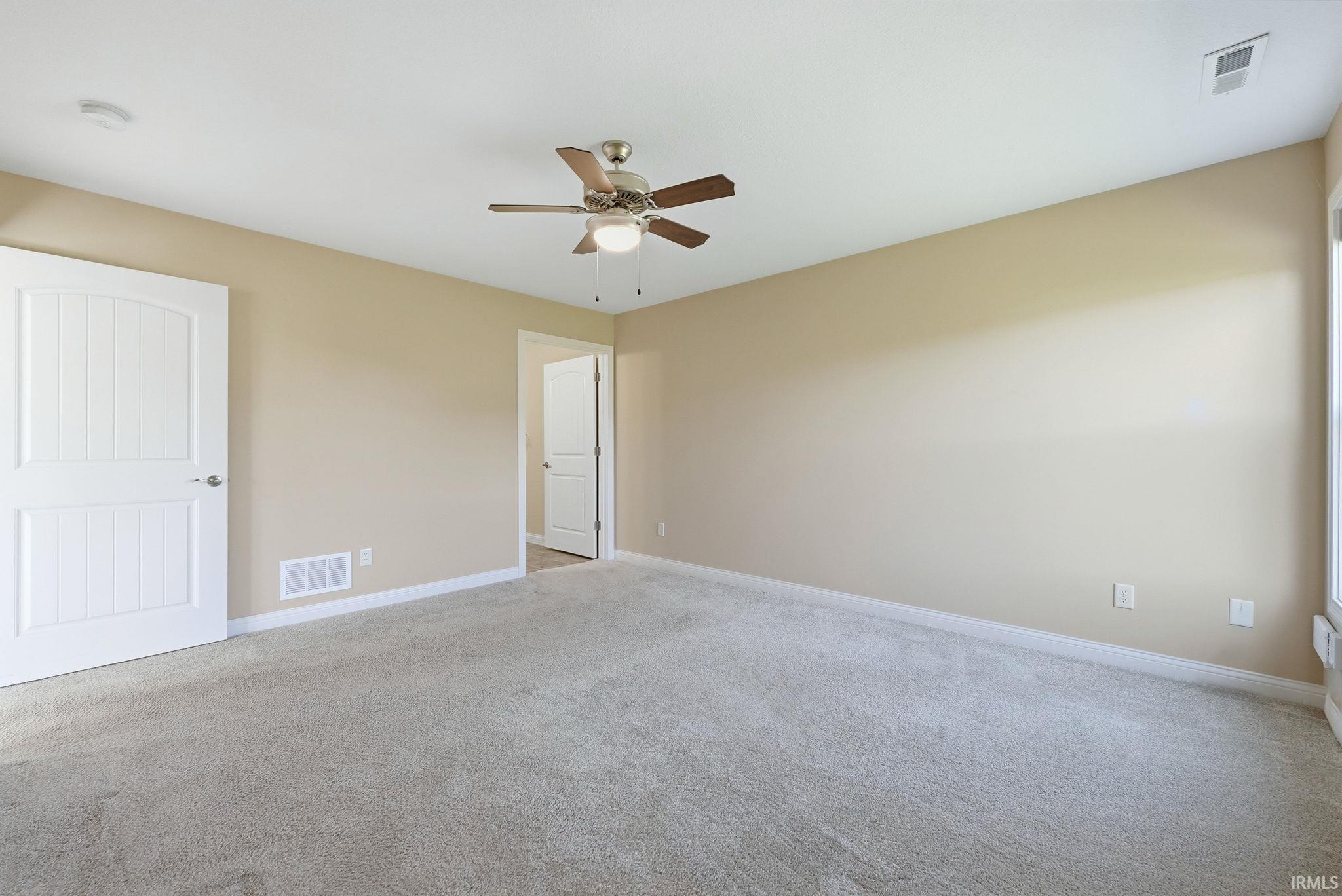 Unfurnished bedroom featuring light carpet and a ceiling fan