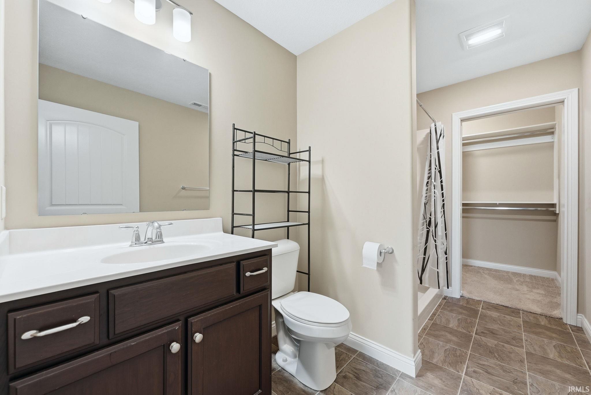 Full bathroom with a shower stall, vanity, and a spacious closet