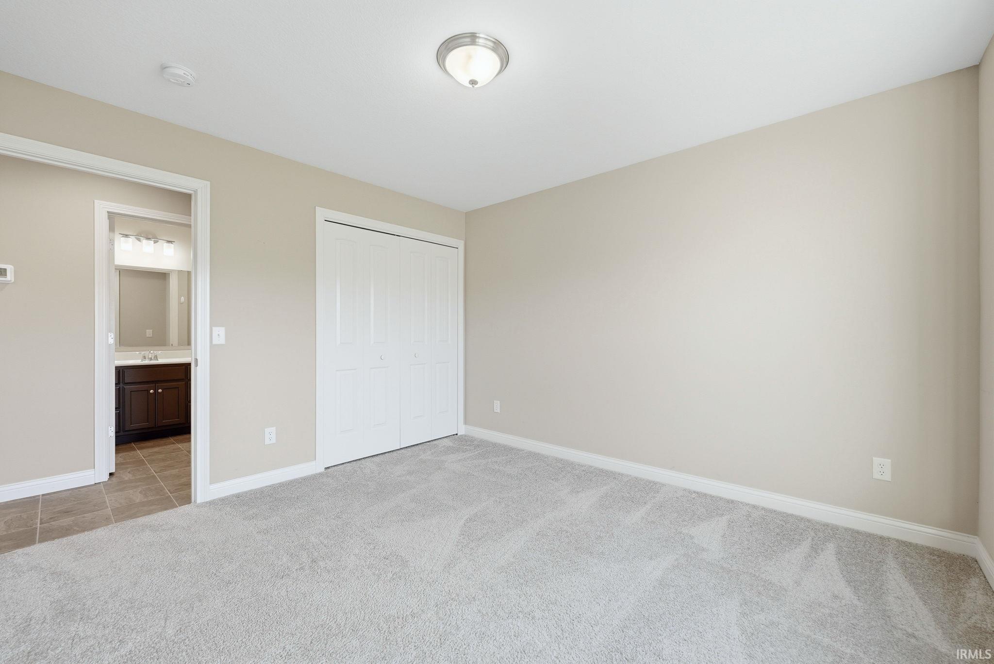 Unfurnished bedroom with light carpet and a closet