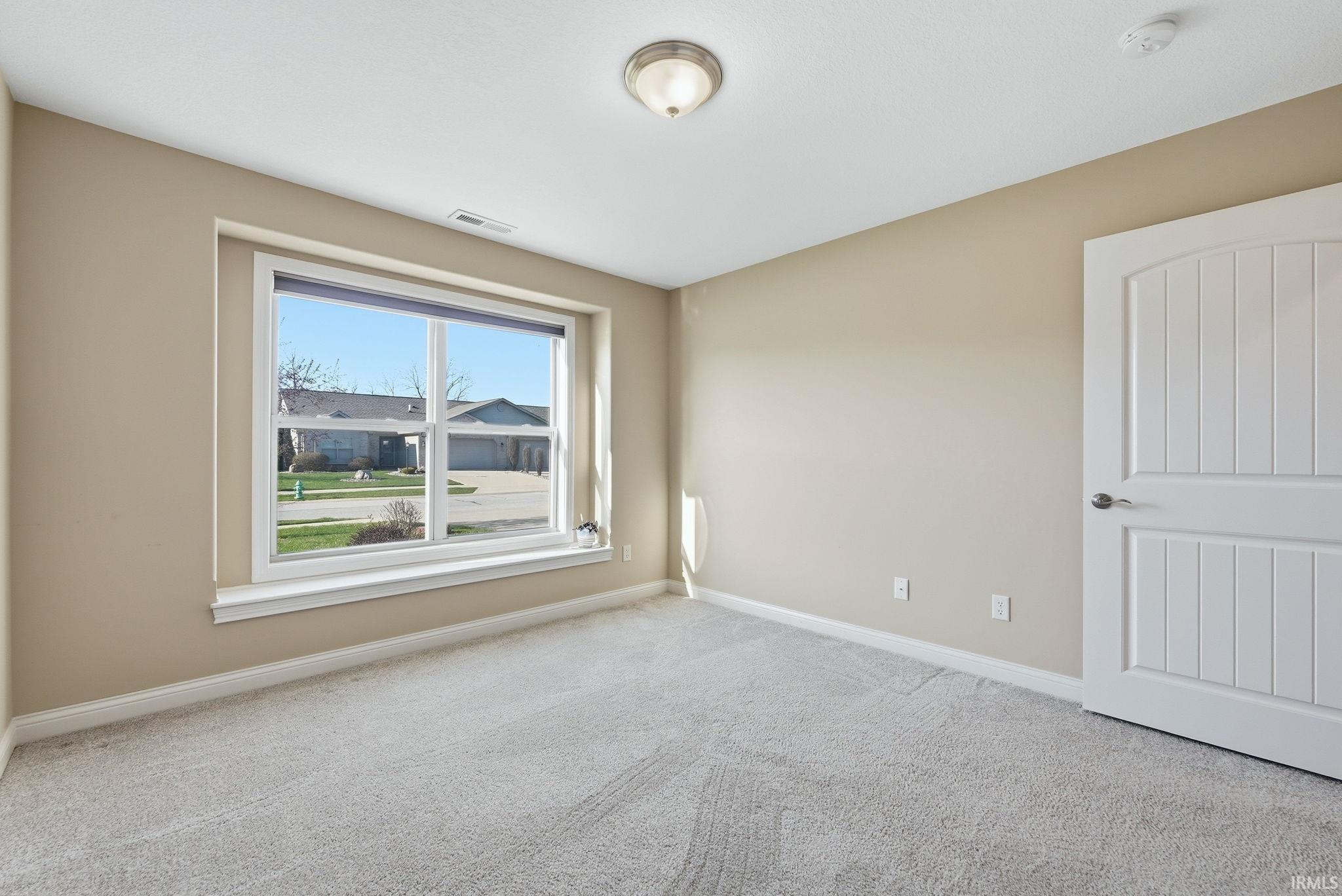 Empty room featuring light colored carpet and baseboards