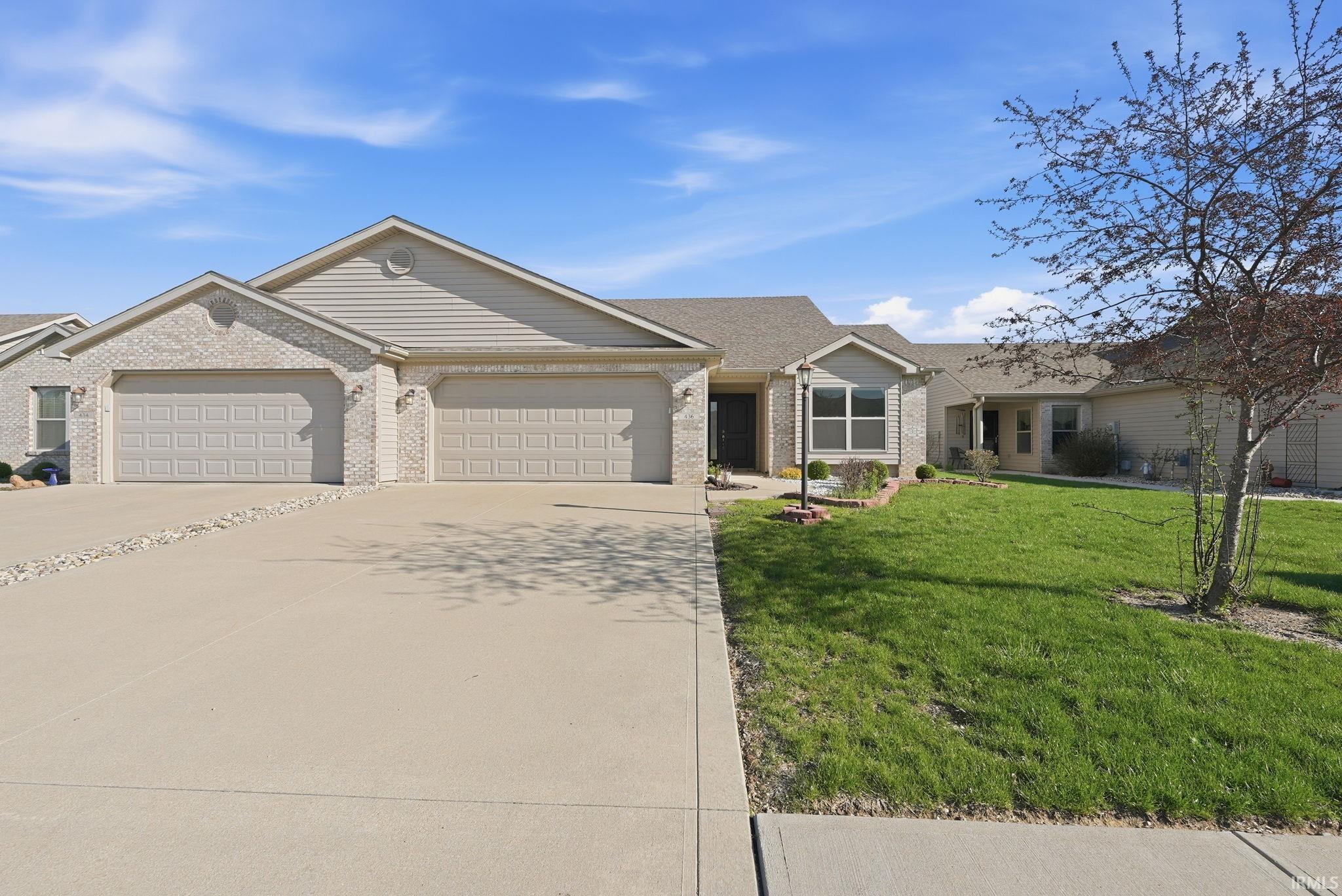 Single story home with concrete driveway, a garage, a front lawn, and brick siding